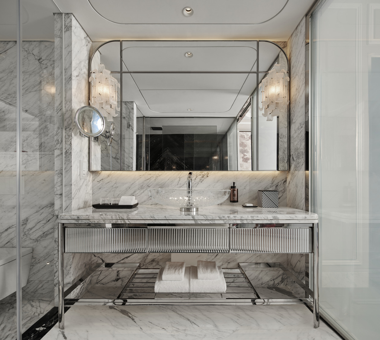 Luxurious hotel restroom with black and white marble walls and floor, featuring geometric patterns. Elegant chandeliers enhance the opulent, sophisticated atmosphere.
