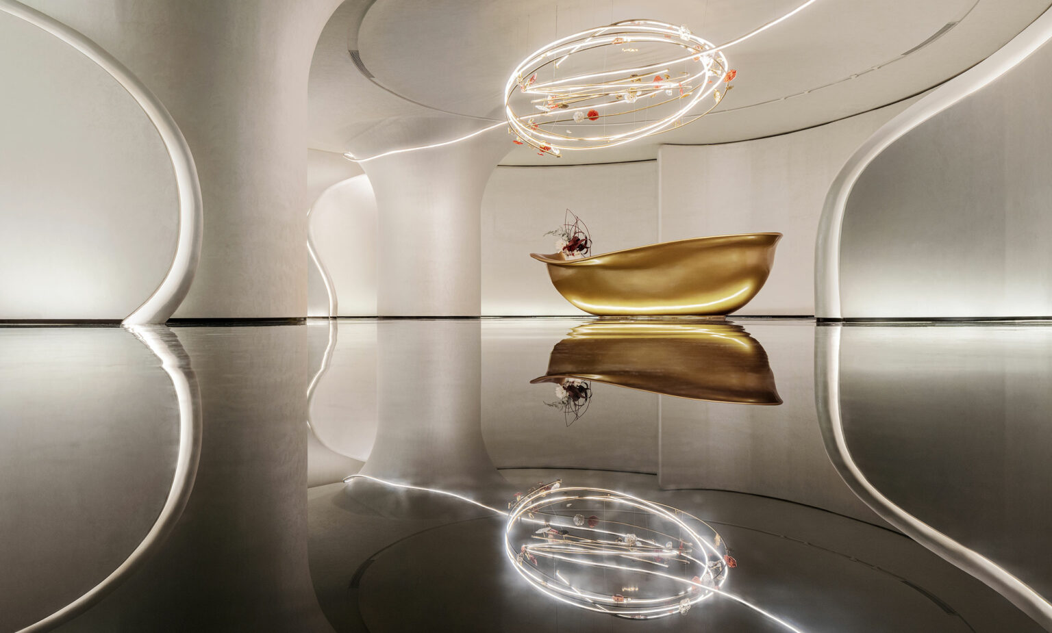 A sleek modern interior with a golden, curved reception desk against a minimalist backdrop. Above, an artistic, spiral light fixture adds elegance.