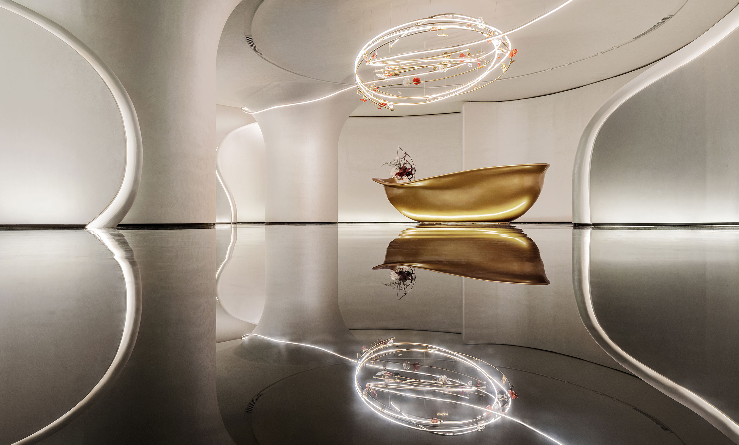 A sleek modern interior with a golden, curved reception desk against a minimalist backdrop. Above, an artistic, spiral light fixture adds elegance.