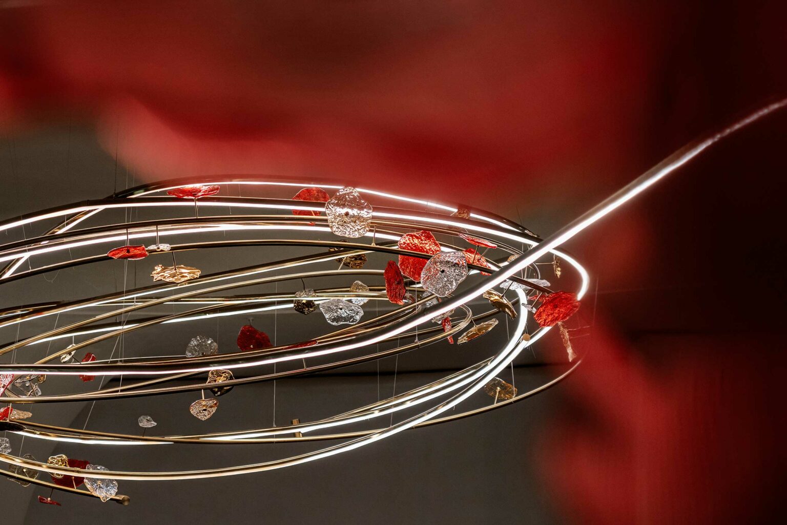 A modern chandelier with glowing circular rings adorned with red and silver glass hearts, creating an elegant and romantic atmosphere.