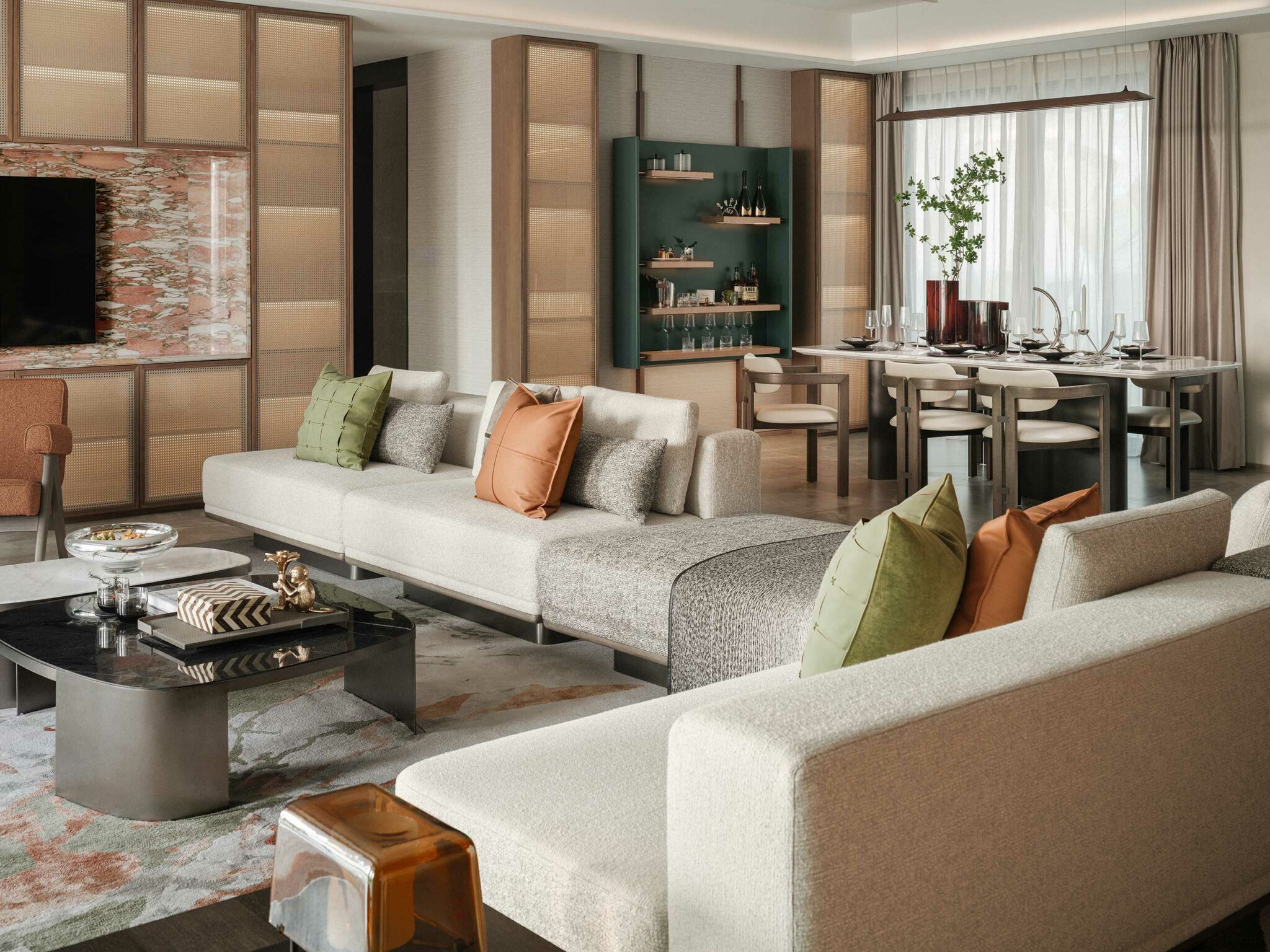 Modern living room with beige sectional sofa adorned with green and orange cushions. A sleek coffee table and adjacent dining area exude elegance.
