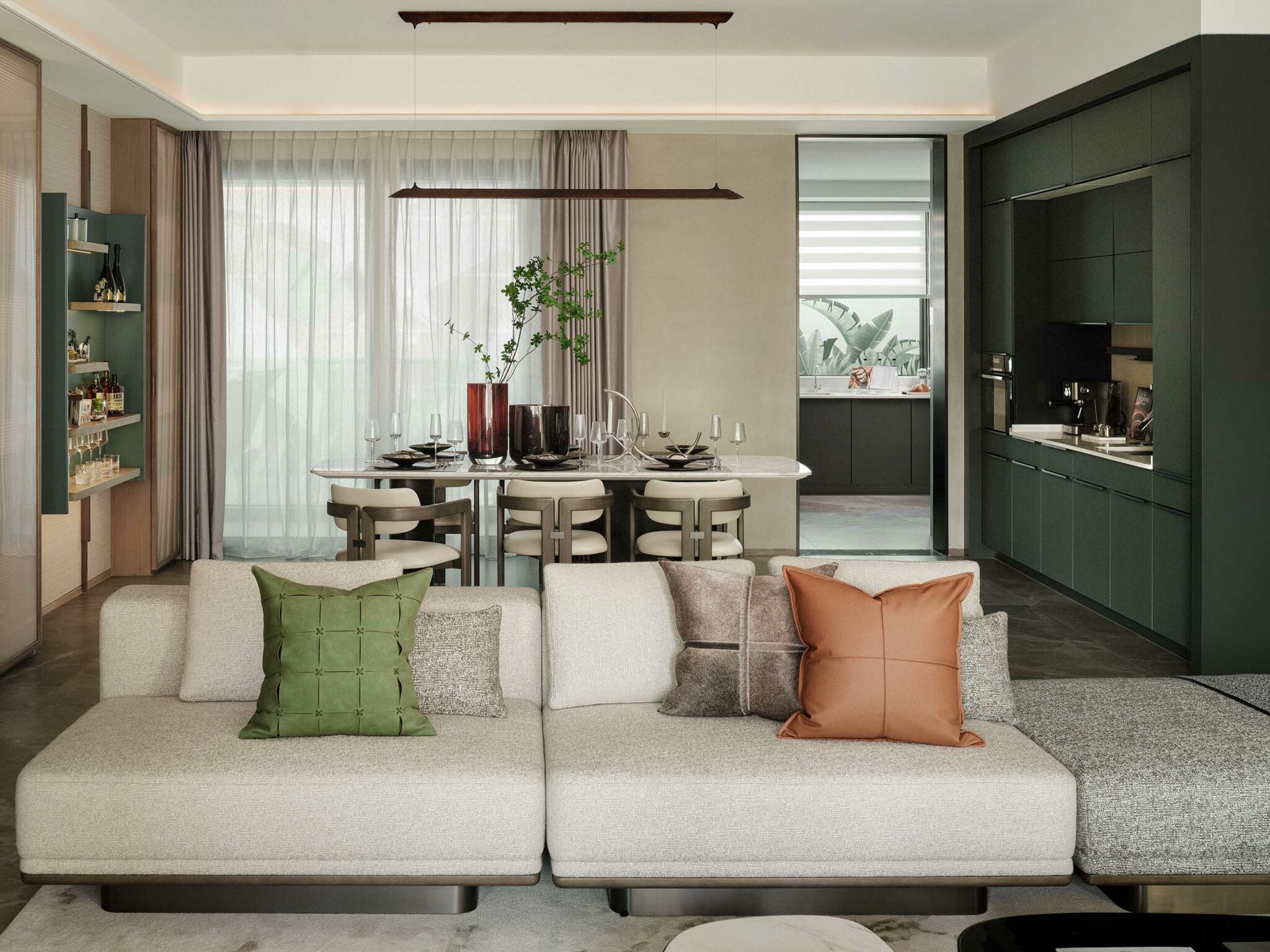 Modern living and dining area with a beige sofa adorned with green and brown cushions. Behind, a table set for dining, and a minimalist kitchen.