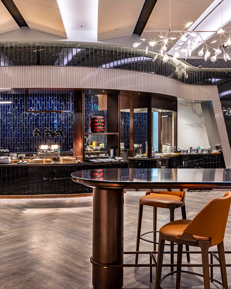 A stylish airline dining area showcasing a sleek buffet counter, modern bar stools, and unique lighting fixtures, creating an inviting ambiance for travelers to enjoy a sophisticated culinary experience.