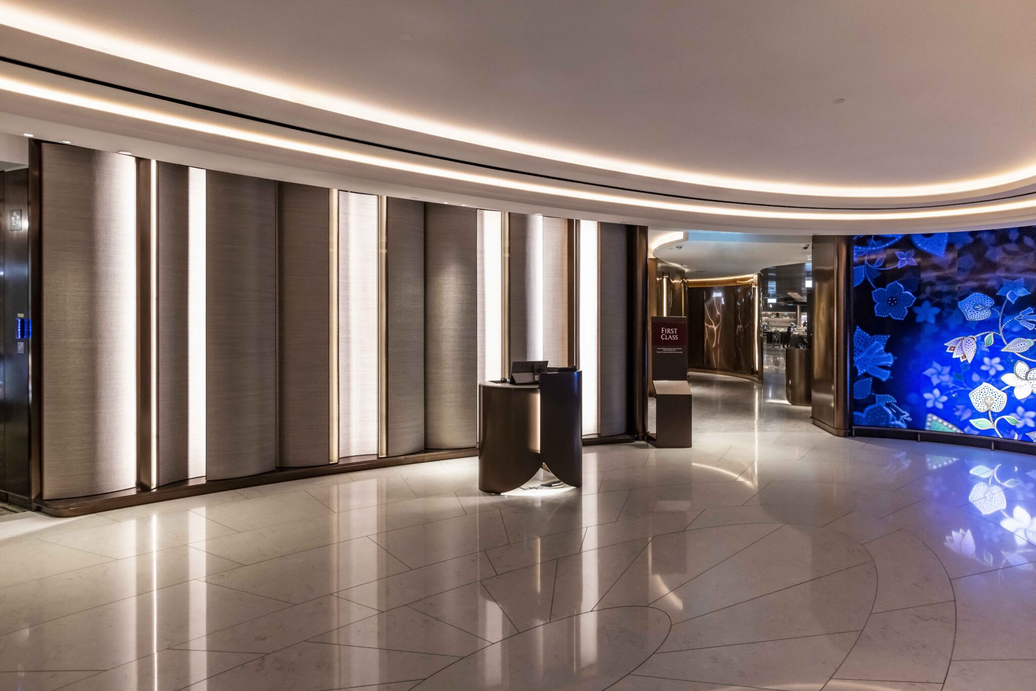 A sleek airline reception area featuring elegant lighting, modern decor, and textured wall panels, creating a sophisticated ambiance that invites guests into an upscale lounge environment.