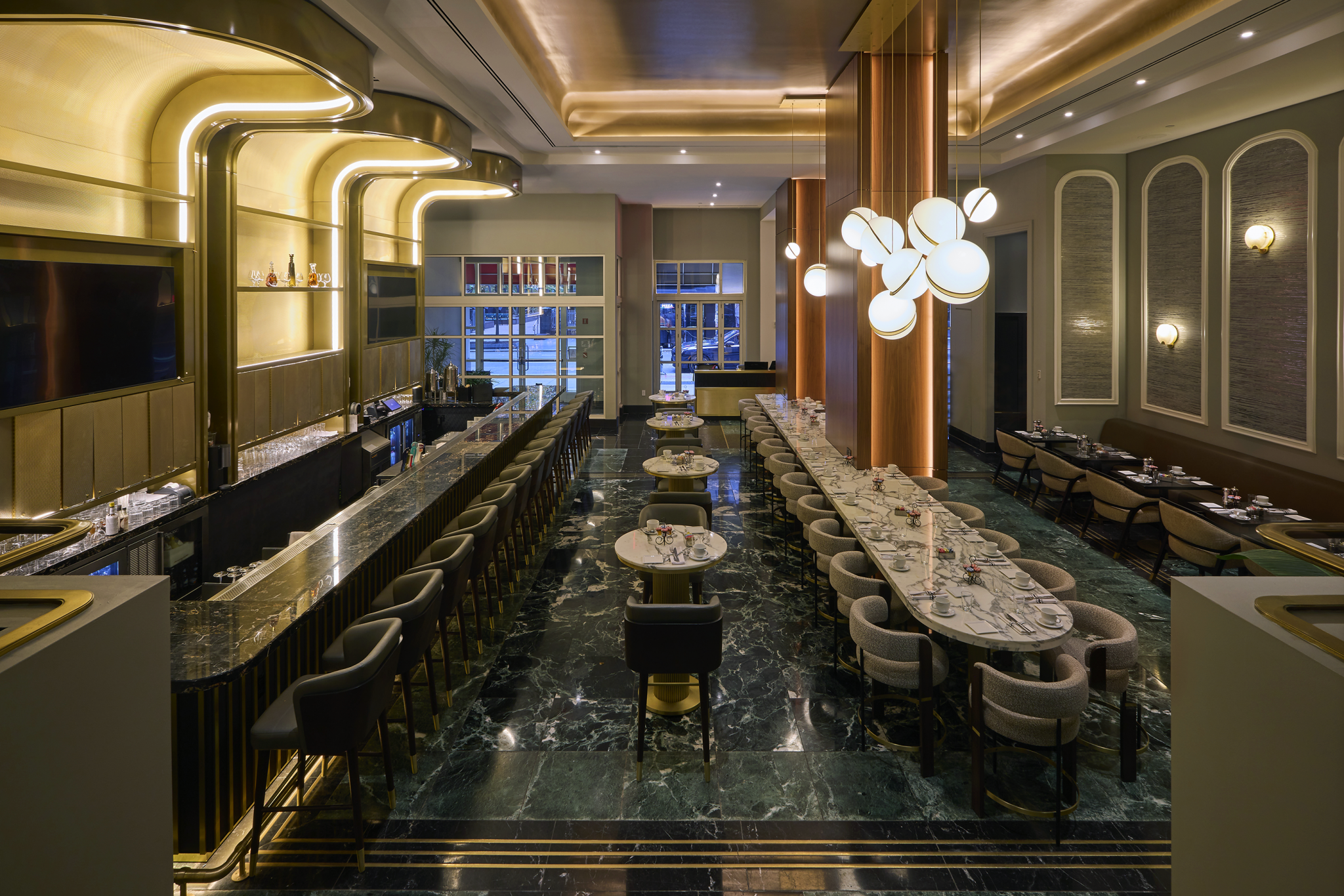 Luxurious restaurant interior with marble tables, elegant bar, plush seating, and modern lighting. The ambiance is warm and sophisticated.