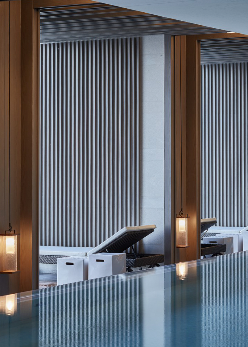 A luxurious indoor swimming pool with sun beds and contemporary sconces.