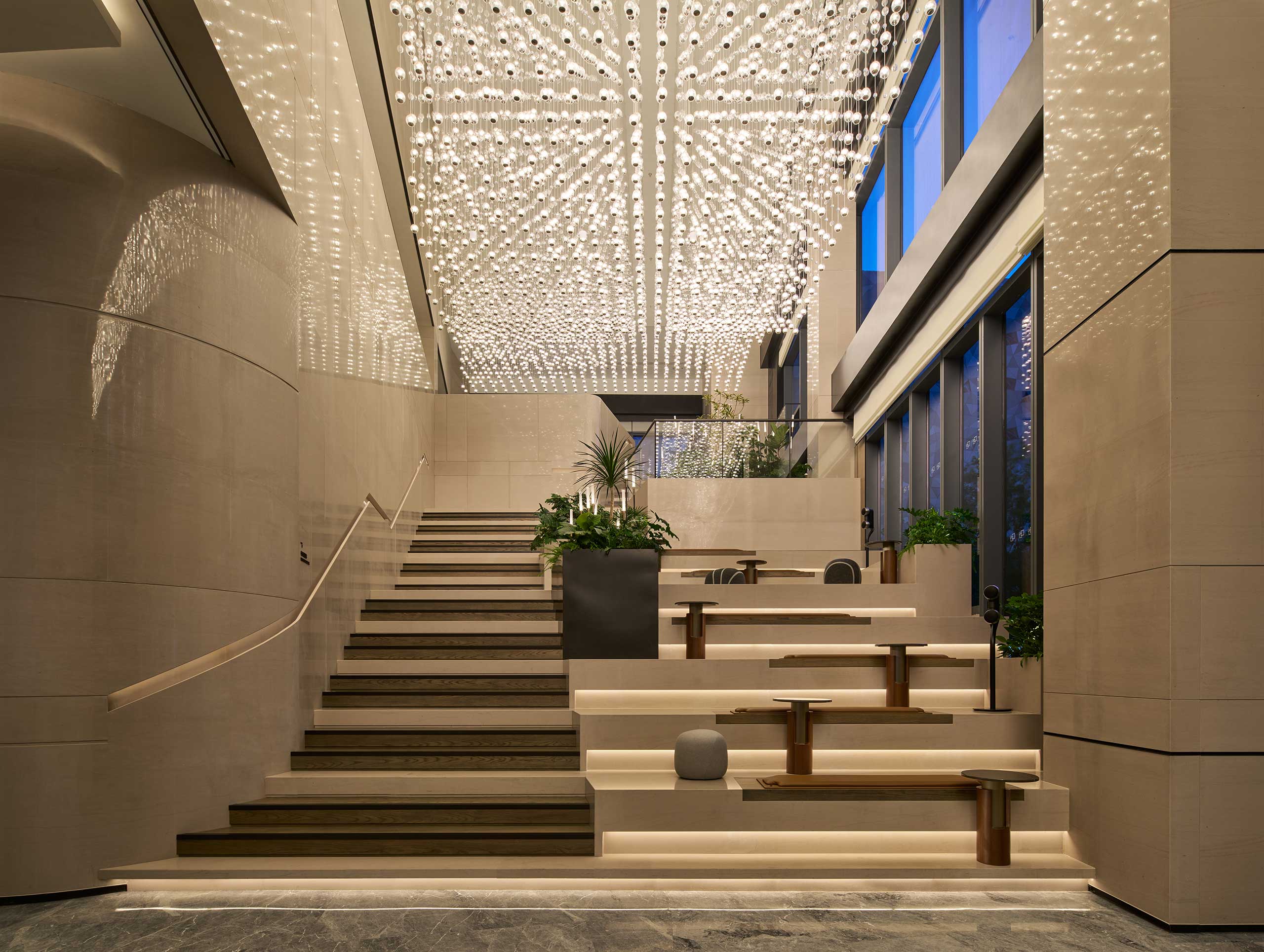 Hilton Shanghai Zhangjiang Science City lobby with modern staircase, tiered seating, indoor plants, and luxury lighting design.