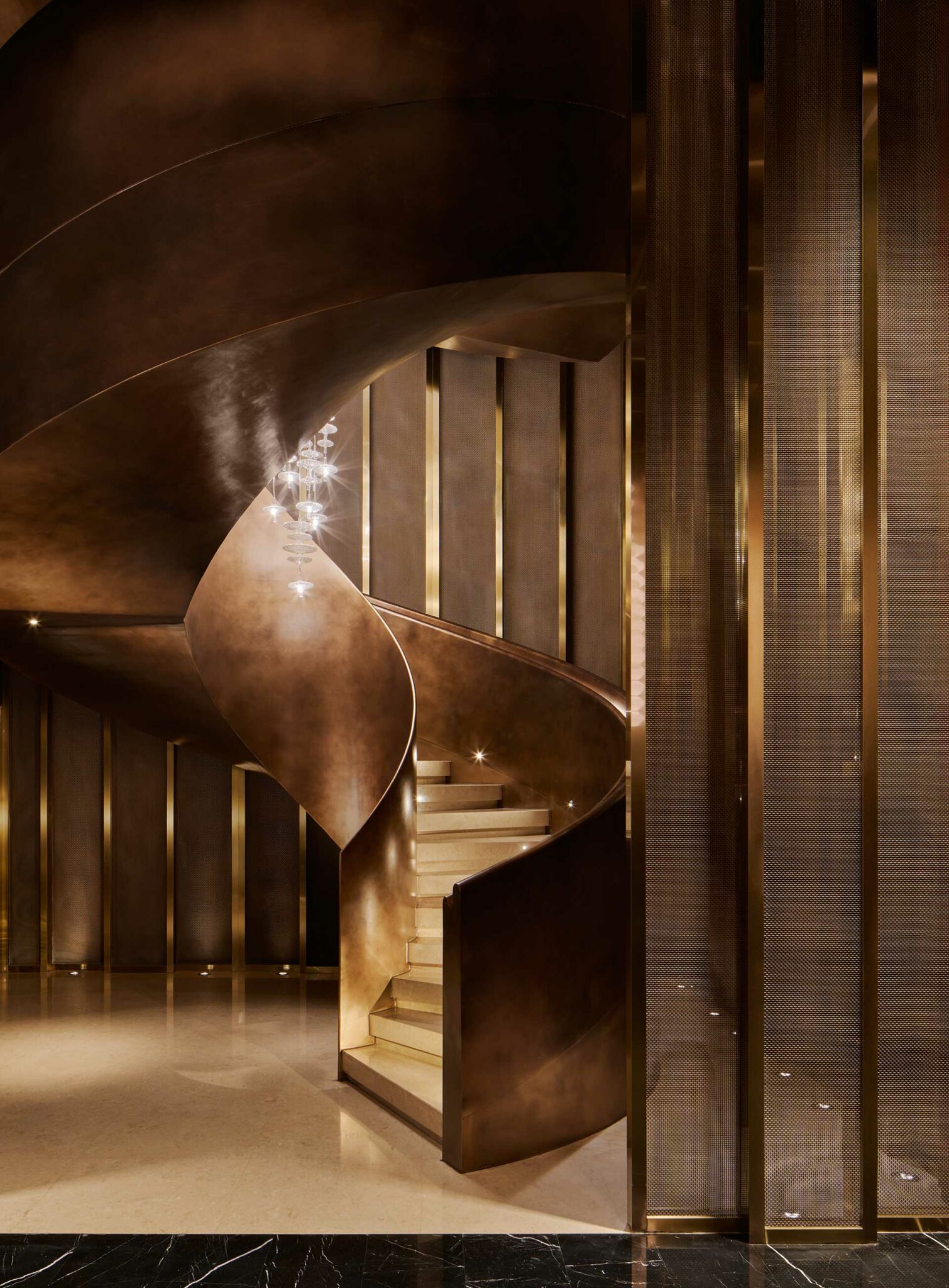 Hilton Shanghai Zhangjiang Science City grand staircase with elegant bronze spiral design and modern chandelier lighting.