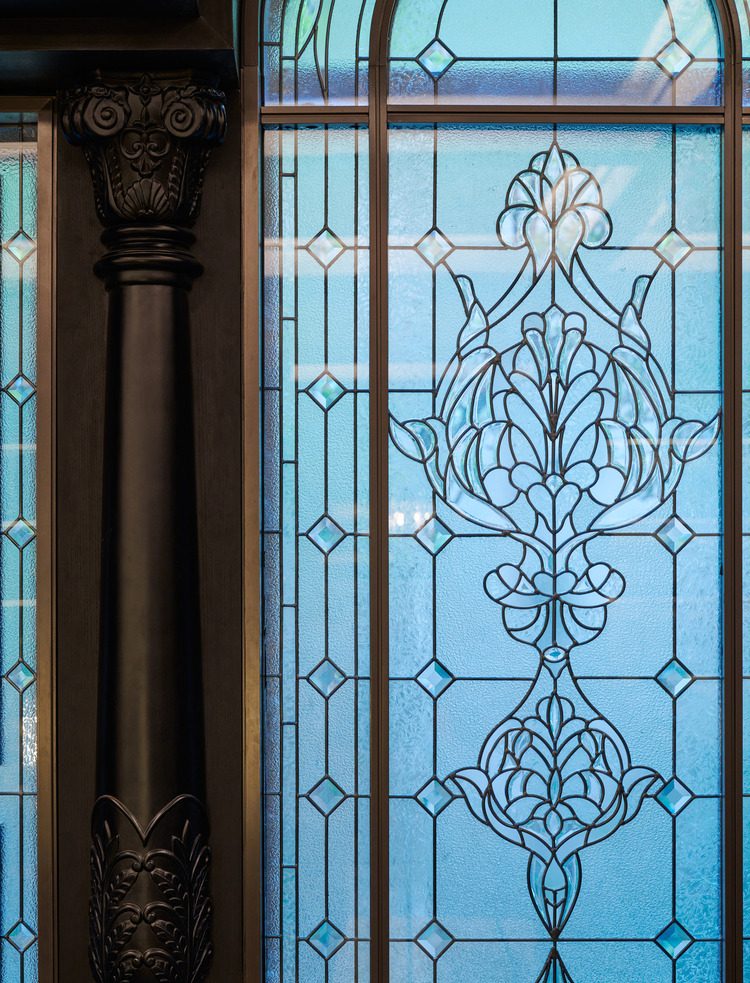Close-up of stained glass window with ornate geometric and floral patterns in shades of blue.