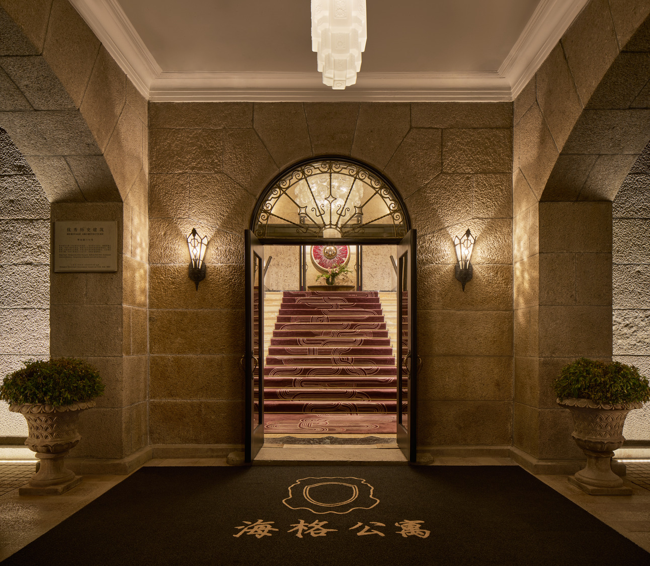 Elegant dark wood entry door with brass details, framed by fluted moulding and wall sconce.