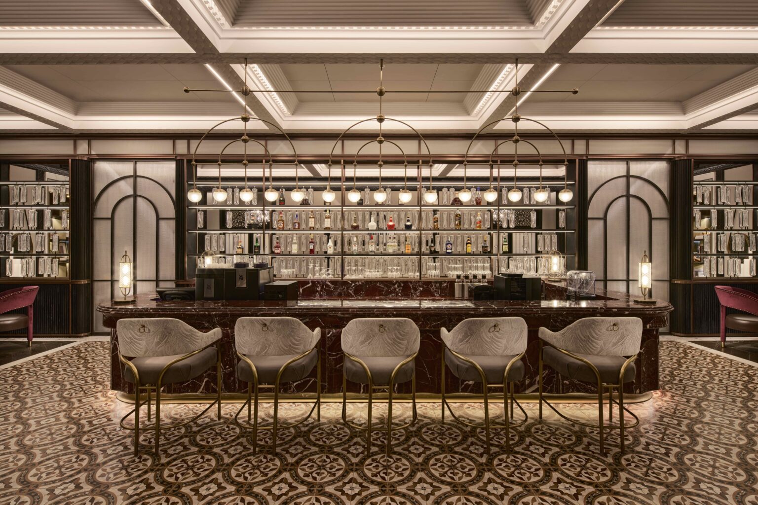 Luxurious restaurant bar counter featuring elegant lighting, a mirror backdrop, leather chairs, and art on dark walls. A sophisticated and inviting ambiance.