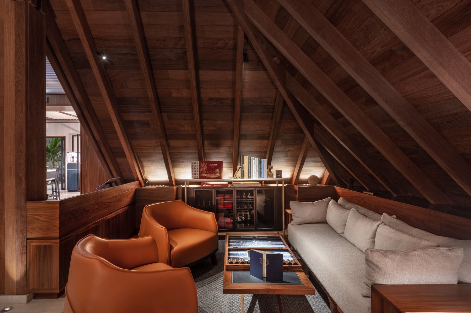 Cozy lounge under timber beams with leather armchairs, sofa seating, and curated books at Ocean Club St Barths.