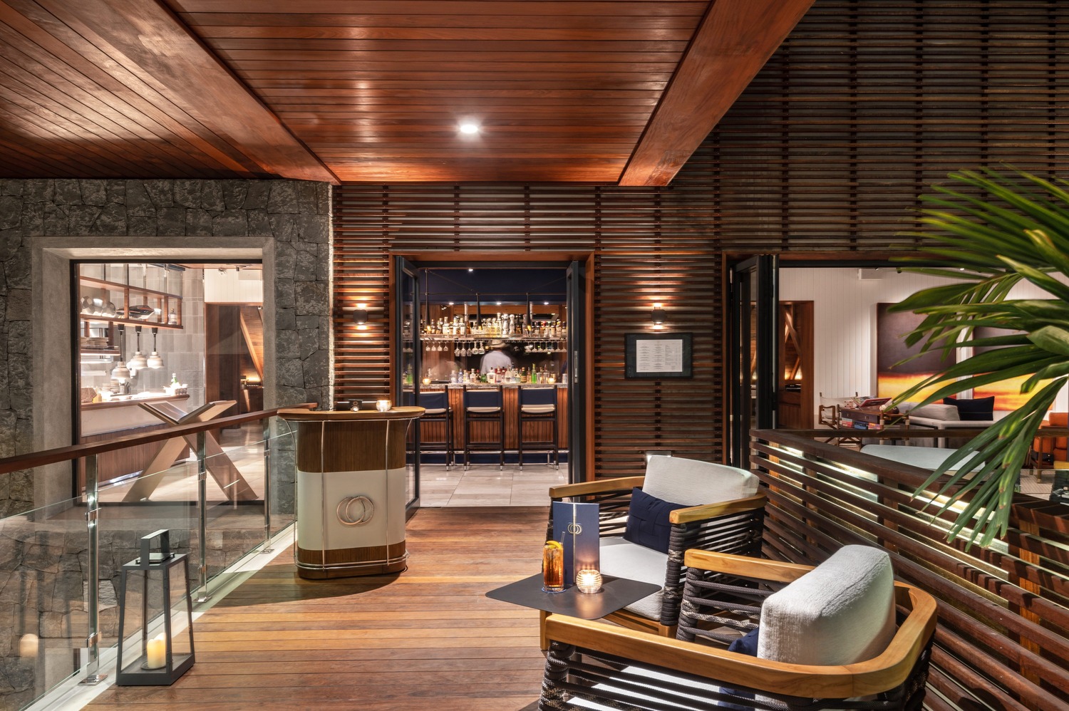 Entryway with stone walls and wooden host stand leading to the cocktail bar at Ocean Club St Barths.