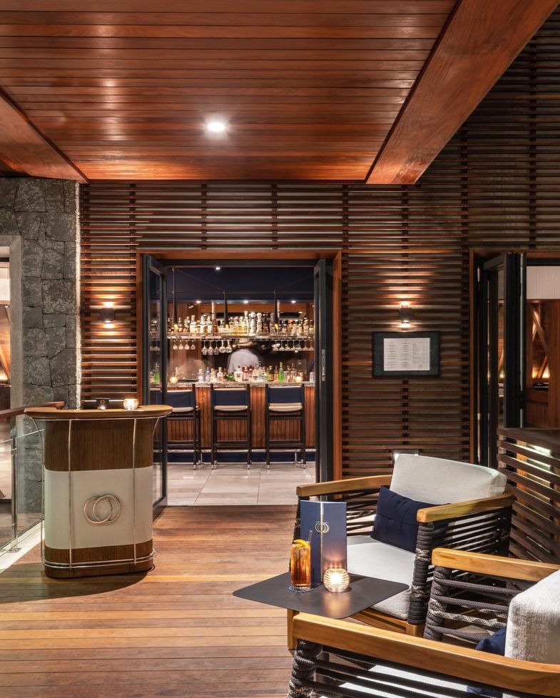 Entryway with stone walls and wooden host stand leading to the cocktail bar at Ocean Club St Barths.