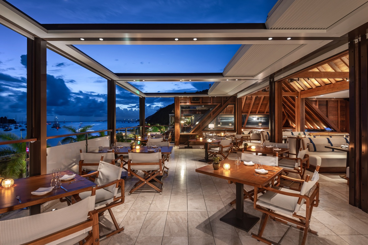 Terrace seating with cushioned chairs, wooden deck, and lantern-lit ambiance at Ocean Club St Barths.