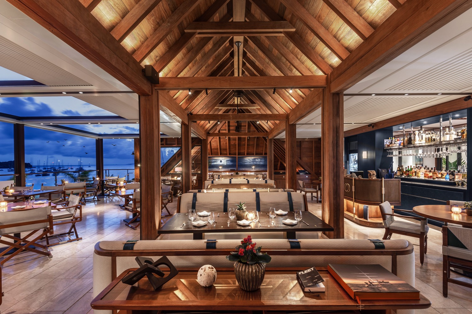 Grand dining hall with vaulted timber ceiling, soft lighting, and ocean views at Ocean Club St Barths.