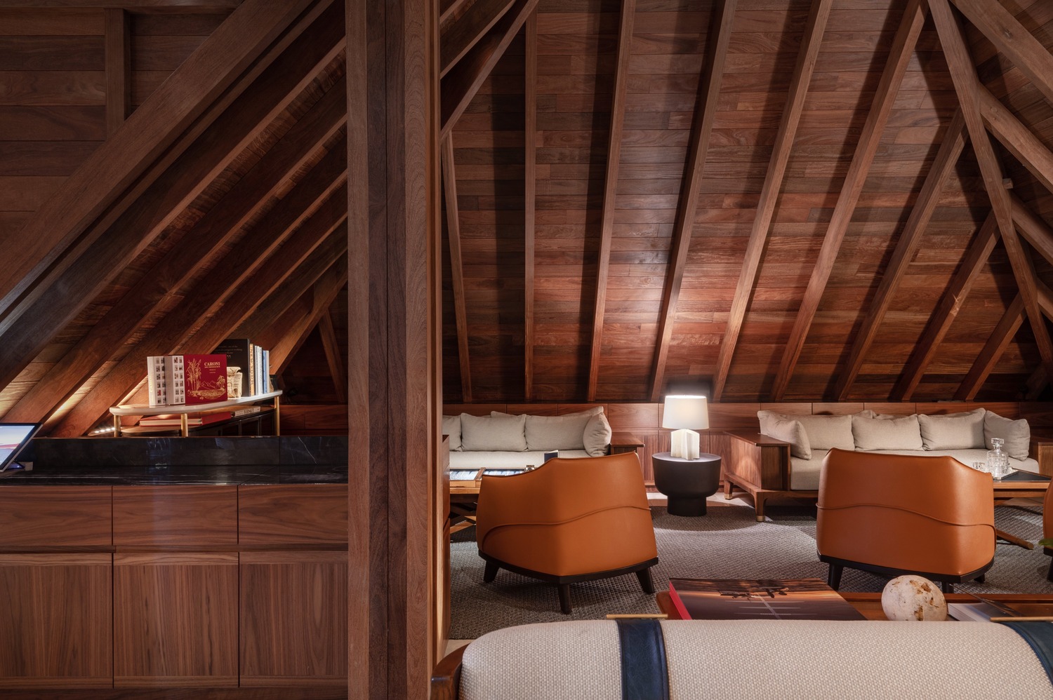 Lounge nook with neutral sofas, leather chairs, and angled wooden beams at Ocean Club St Barths.
