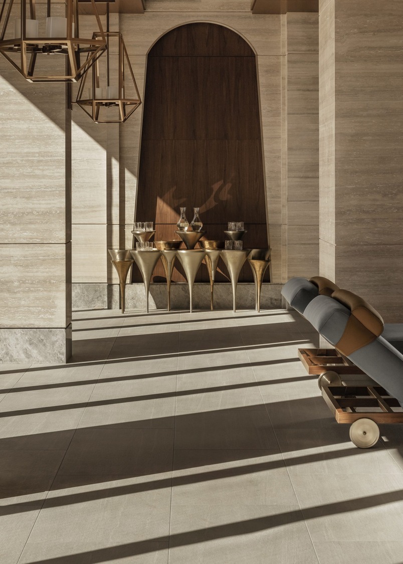 Luxurious resort spa interior with arched golden doorways and marble walls. A person in a white robe walks through the opulent, serene hallway.