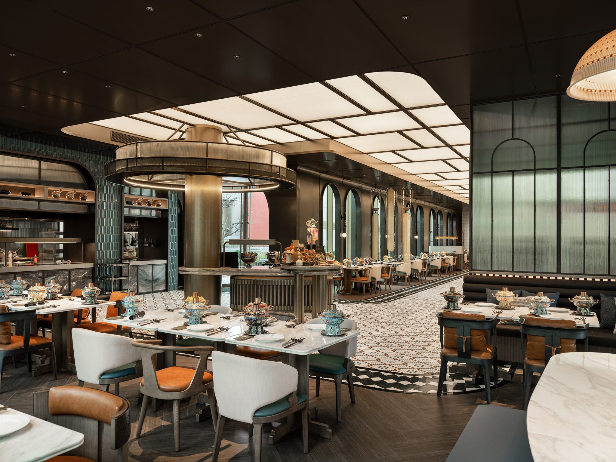 Stylish, modern restaurant interior with elegant tables set for dining, leather chairs, soft lighting, and a patterned floor creating a cozy atmosphere.