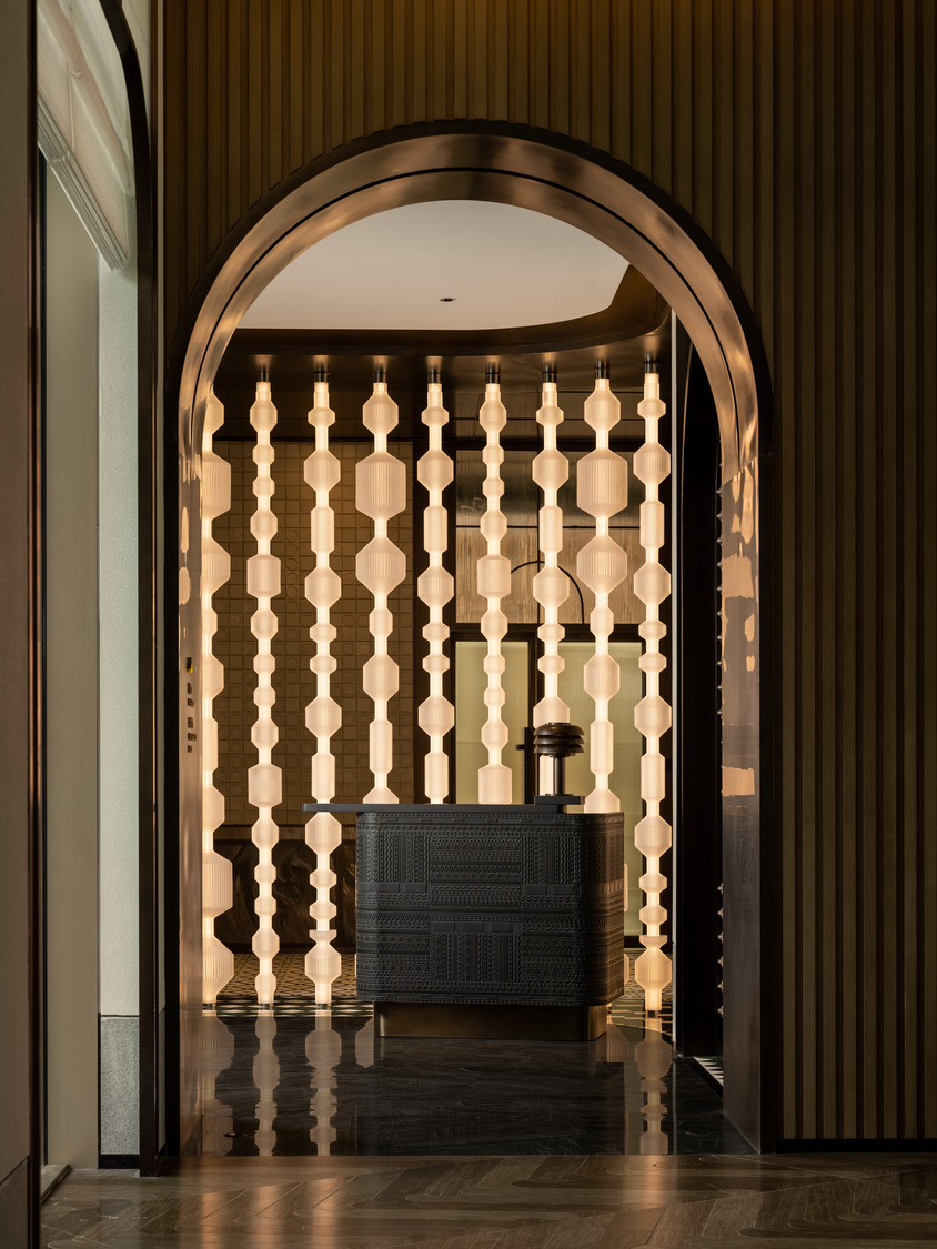 Luxurious hotel lobby with high ceiling and string lights. Features elegant sofas, coffee tables, and potted trees. Airy and sophisticated ambiance.