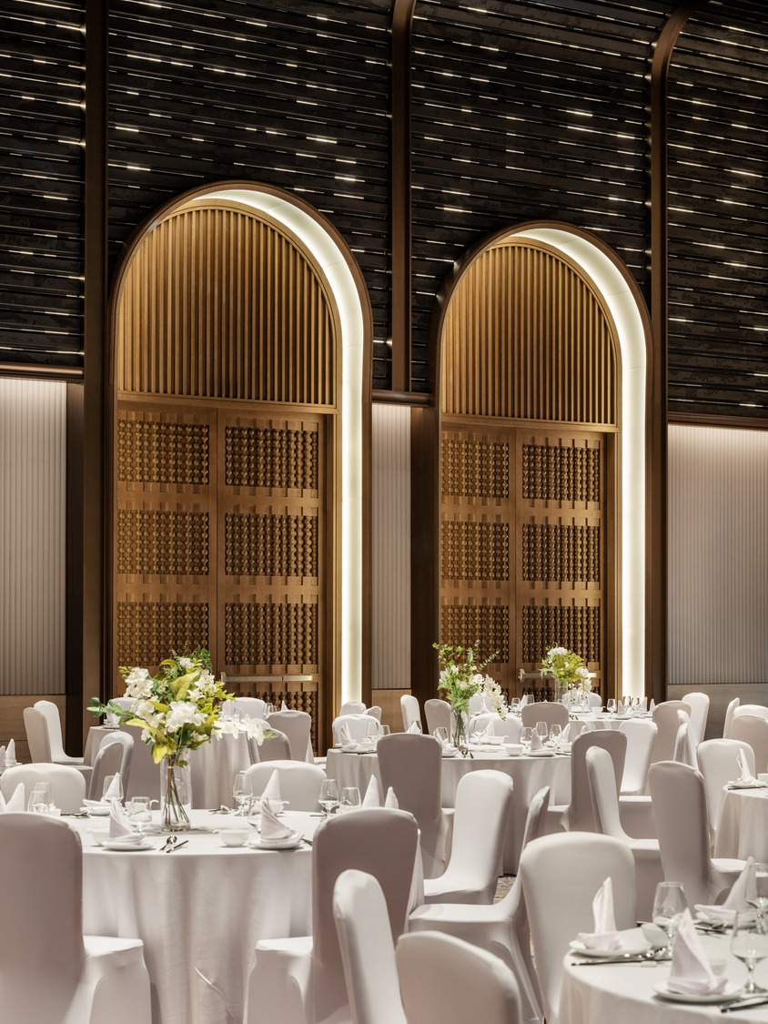 A grand hotel lobby featuring a dramatic chandelier, elegant seating areas, and a sweeping staircase, creating a luxurious and inviting atmosphere for guests to relax and socialize.