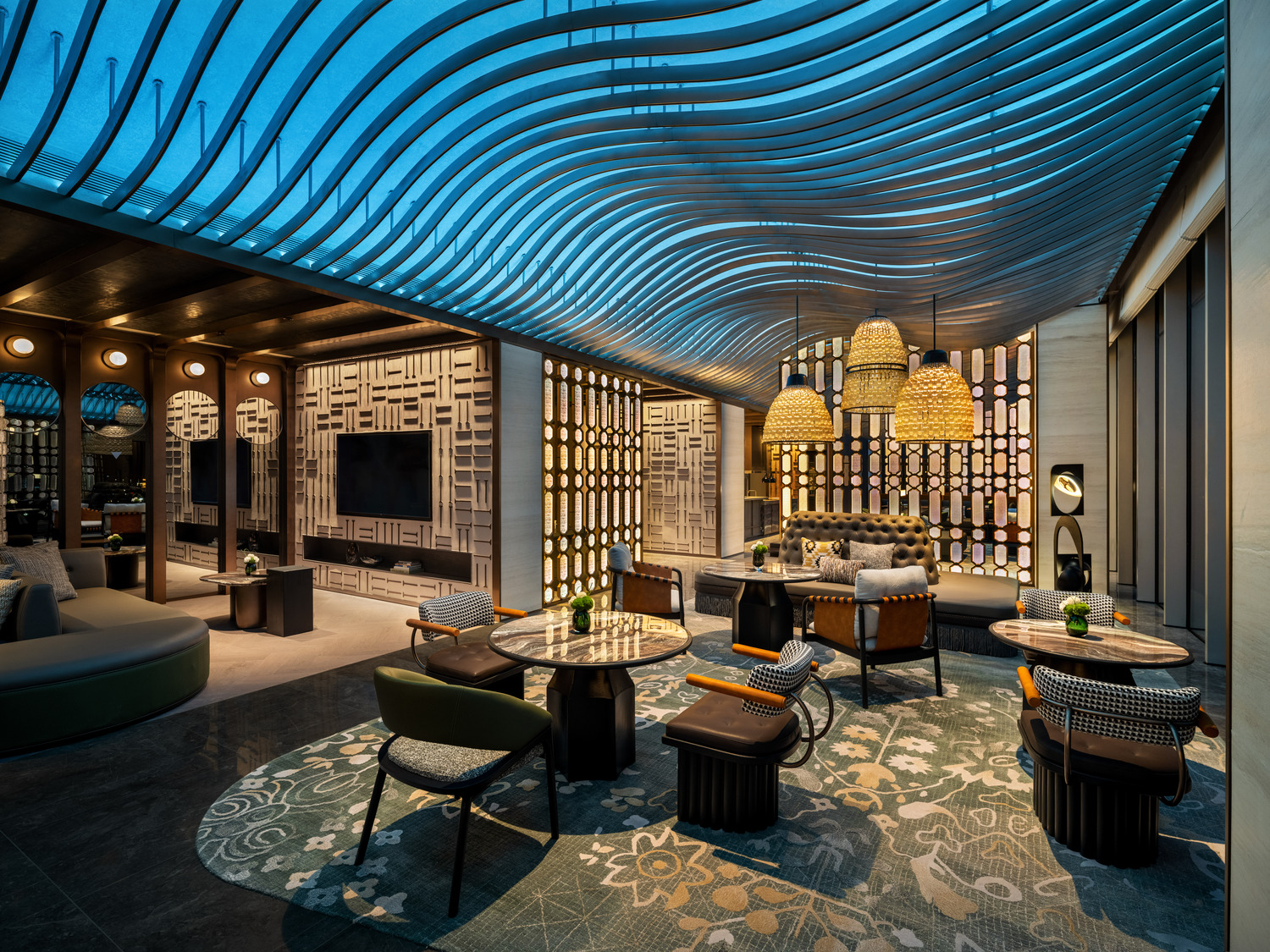 A grand hotel lobby featuring a dramatic chandelier, elegant seating areas, and a sweeping staircase, creating a luxurious and inviting atmosphere for guests to relax and socialize.