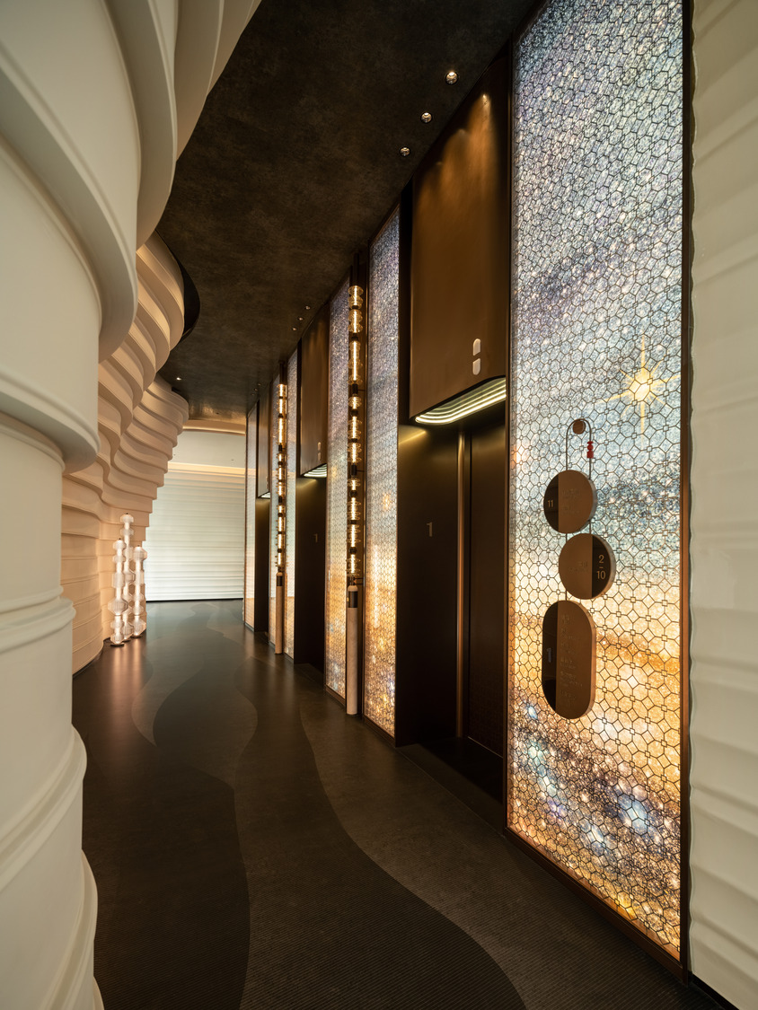 A grand hotel lobby featuring a dramatic chandelier, elegant seating areas, and a sweeping staircase, creating a luxurious and inviting atmosphere for guests to relax and socialize.