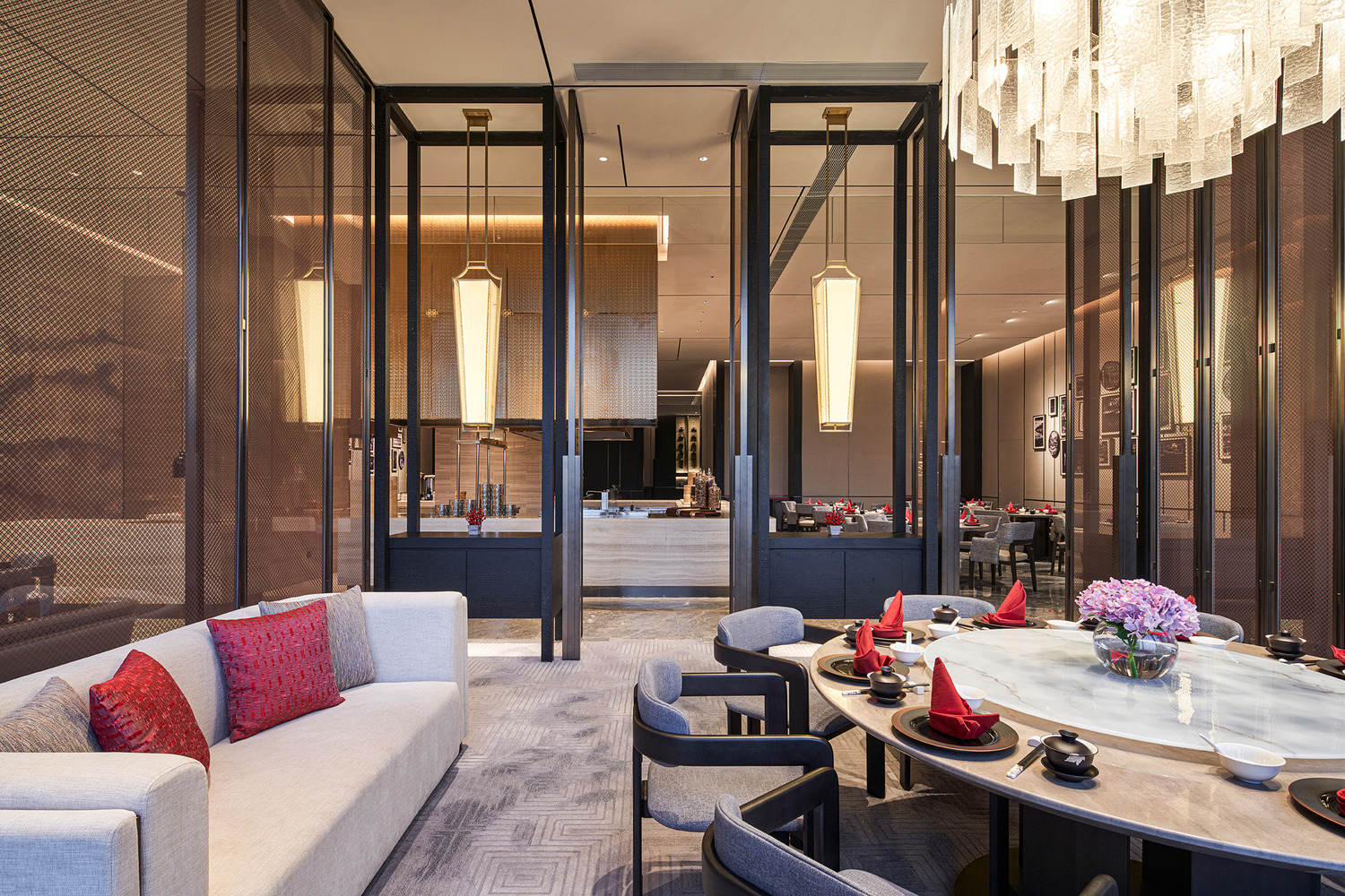 Elegant modern restaurant interior within a luxurious resort featuring geometric ceiling lights, wooden floors, and stylish beige chairs around round tables, creating a warm, inviting ambiance.