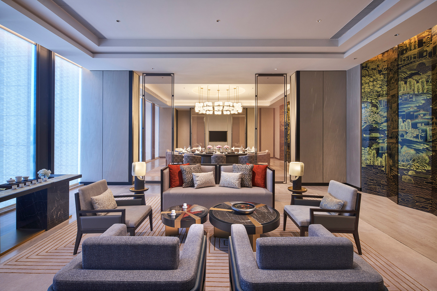 Elegant modern restaurant interior within a luxurious resort featuring geometric ceiling lights, wooden floors, and stylish beige chairs around round tables, creating a warm, inviting ambiance.