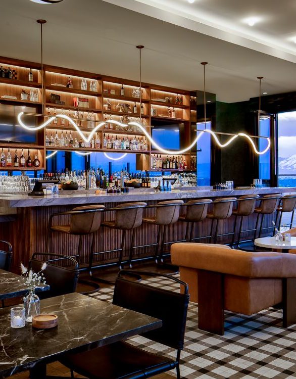 Luxurious hotel lounge with elegant furniture, soft lighting, and a marble bar. The modern design features curved architecture, plush seating, and warm tones.
