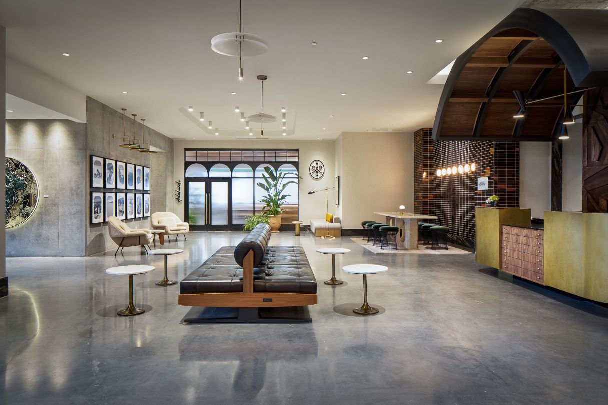 elegant hotel lounge with dim lighting, featuring round tables, plush chairs, and a sleek bar in the background. The ambiance is cozy and sophisticated.