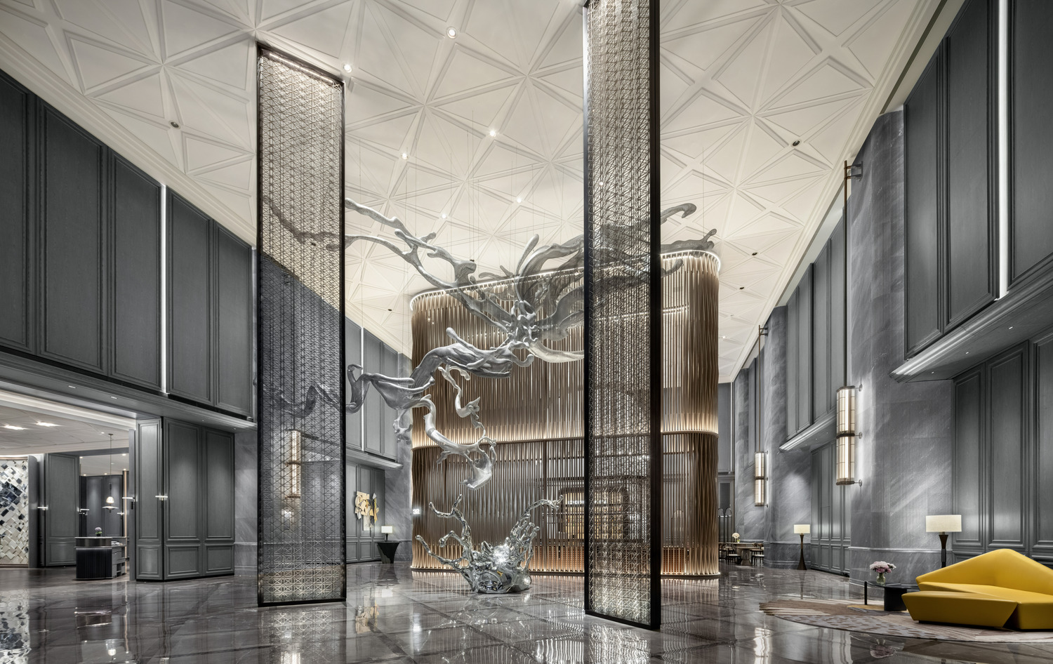 Luxurious hotel lobby with a grand, artistic chandelier cascading from the ceiling. Elegant furniture, soft lighting, and wall art create a sophisticated ambiance.