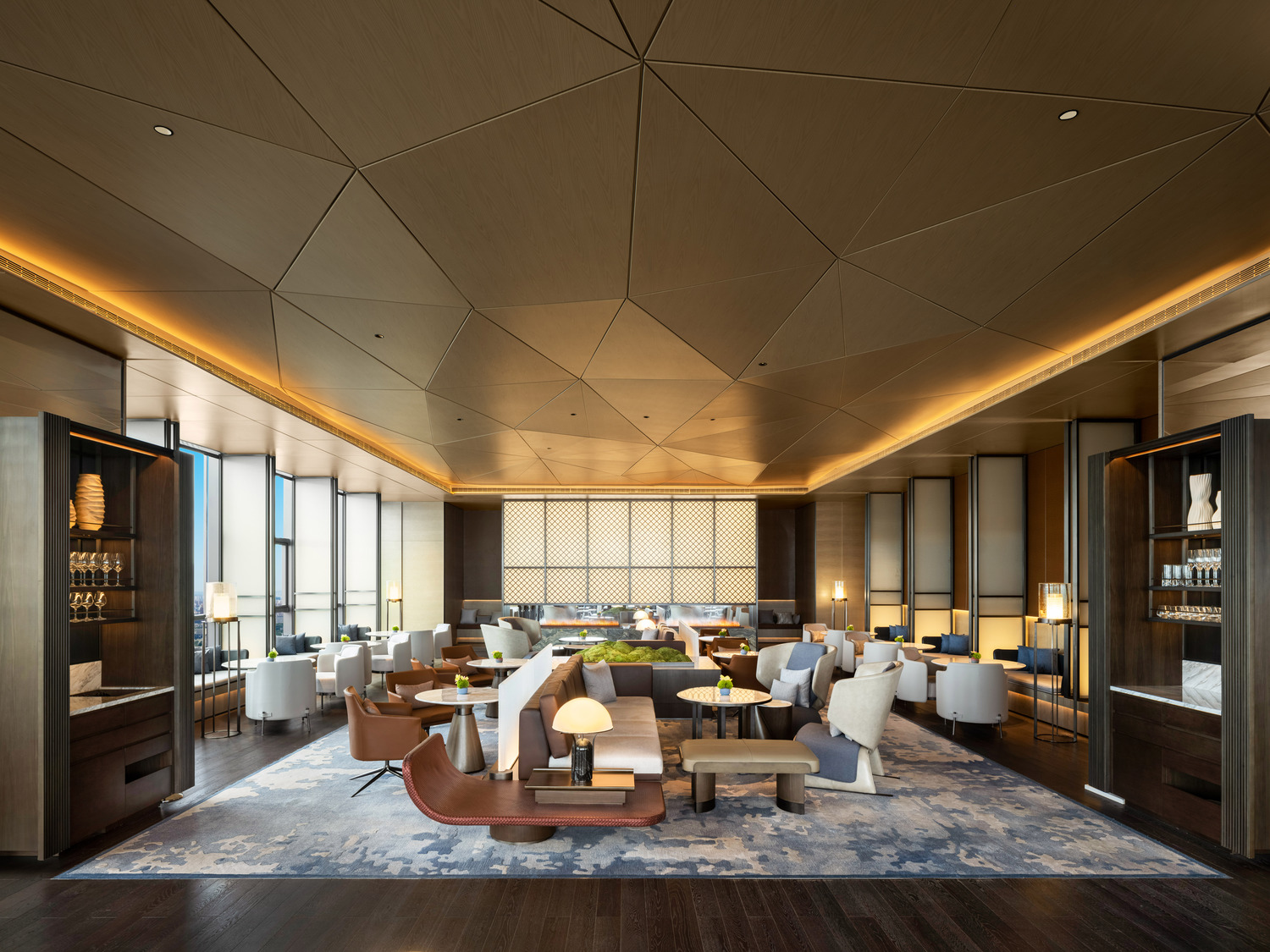 Elegant modern restaurant interior within a luxurious resort featuring geometric ceiling lights, wooden floors, and stylish beige chairs around round tables, creating a warm, inviting ambiance.
