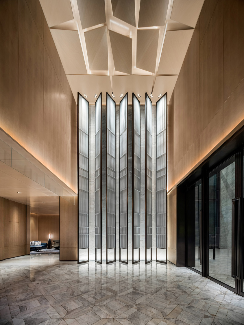 Modern hotel lobby with a sleek marble reception desk, vibrant teal and red shelving, elegant lighting, and a lush indoor tree. The space conveys luxury.