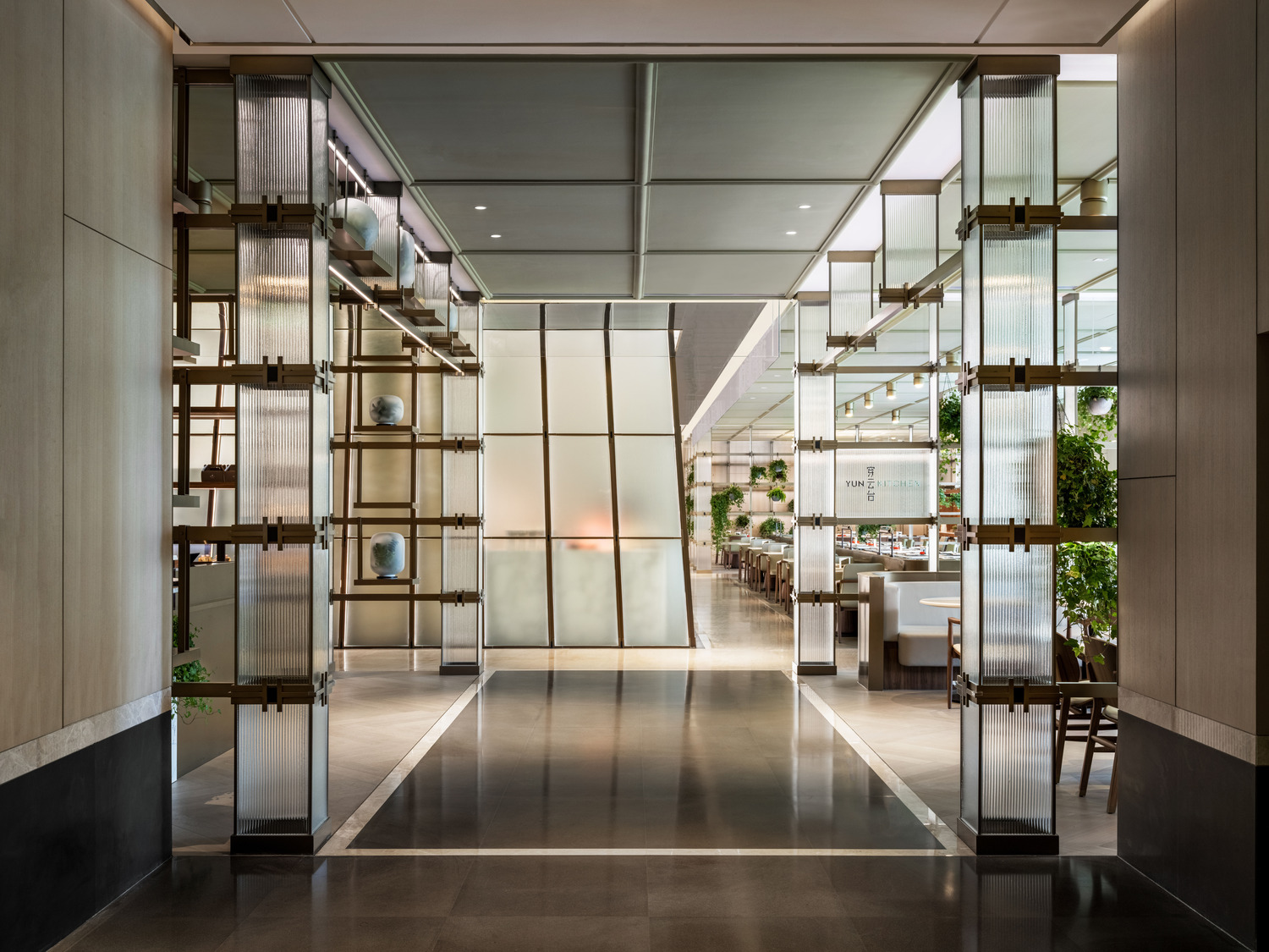 Elegant modern restaurant interior within a luxurious resort featuring geometric ceiling lights, wooden floors, and stylish beige chairs around round tables, creating a warm, inviting ambiance.