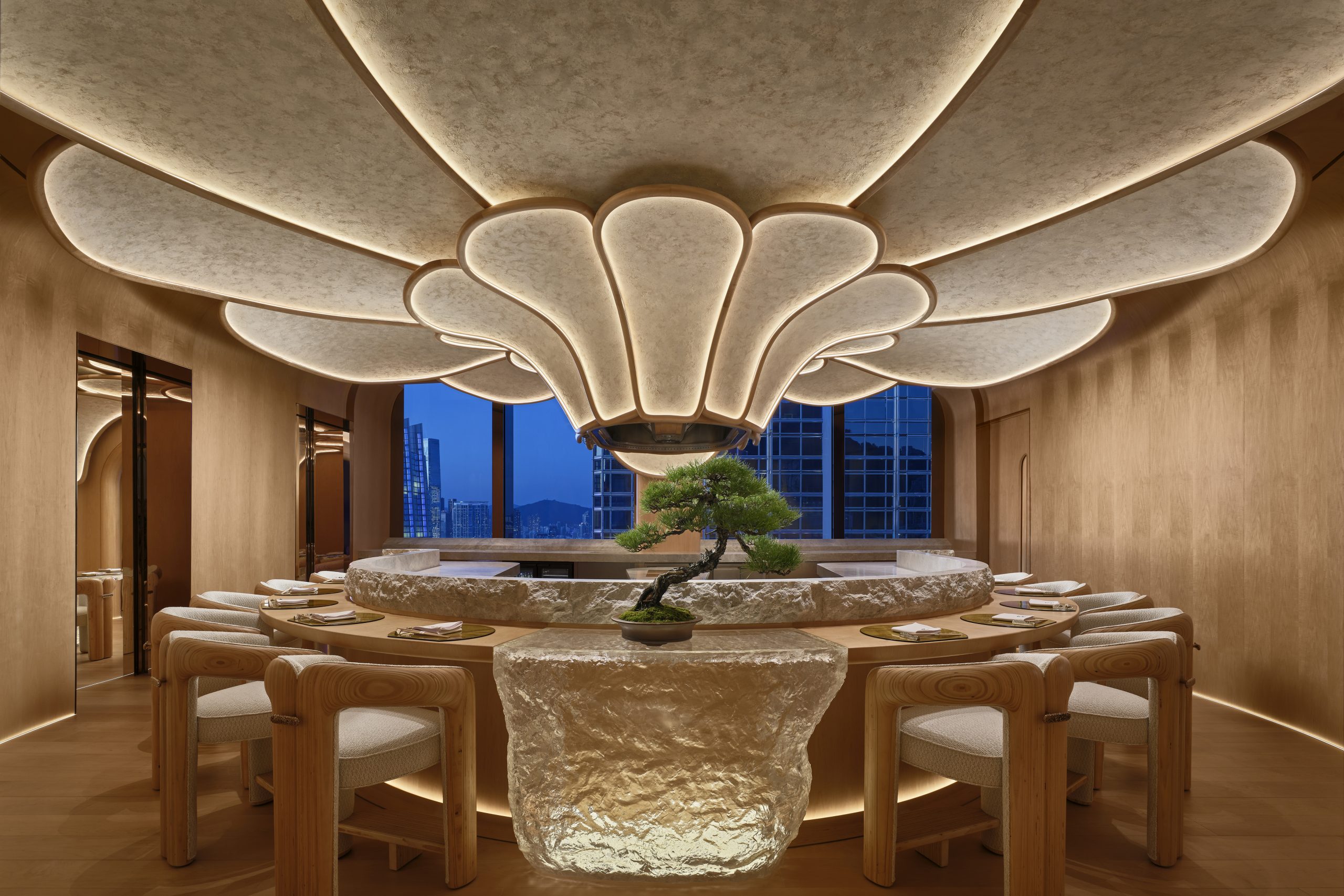 1. Elegant dining room with a nature-inspired ceiling resembling a flower, centered bonsai tree on stone table, wooden chairs, and evening cityscape view.