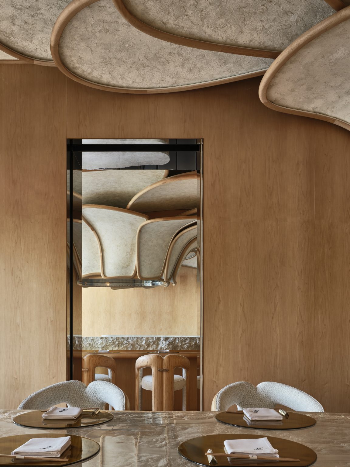 8. Modern restaurant interior featuring a marble table set with napkins, rounded chairs, and a wooden panel. The ceiling's wavy design is mirrored creatively.