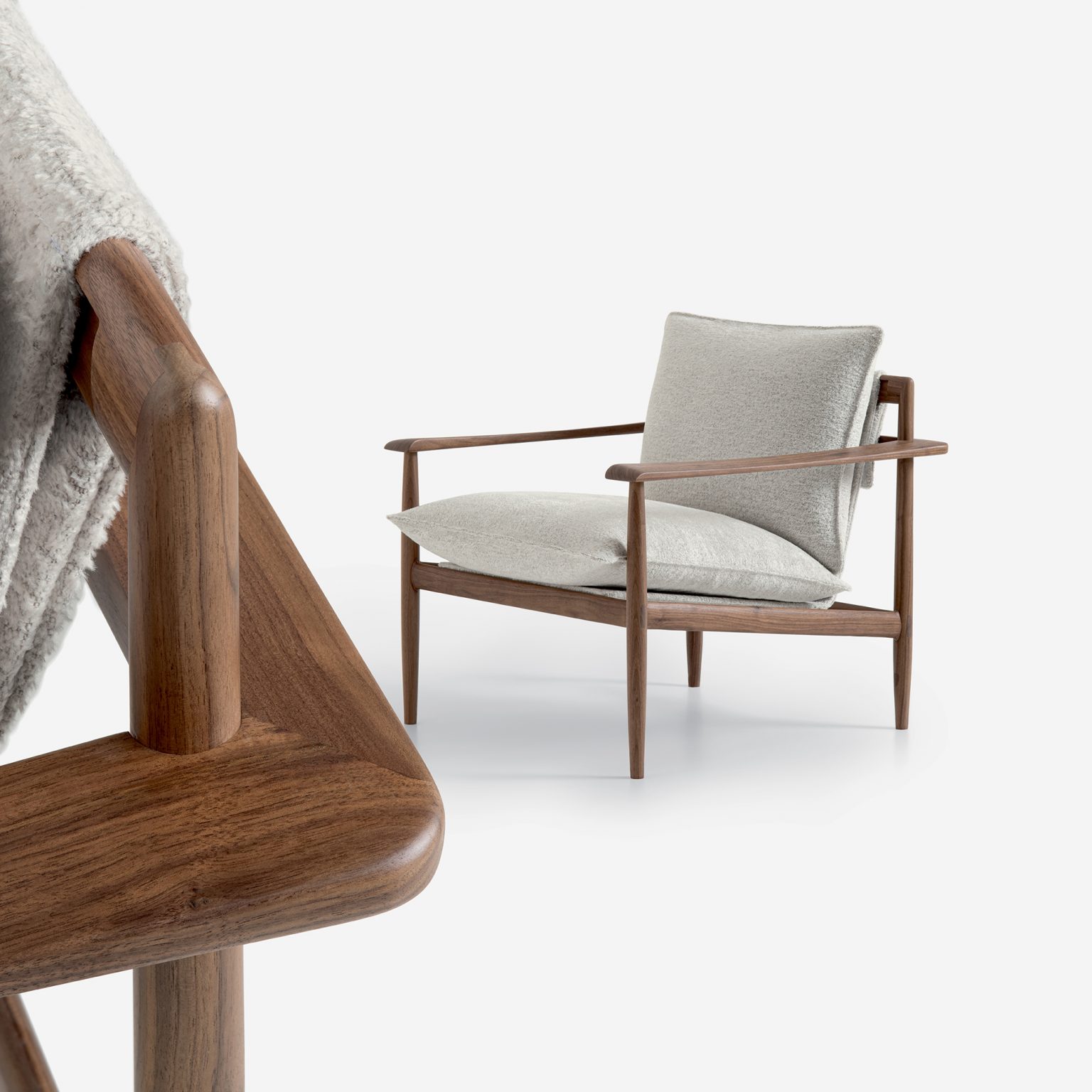 Giorgetti - KUMIKI's modern armchair with wooden frame and soft gray cushions, set against a white background. Close-up shows a cozy gray blanket draped over the armrest.