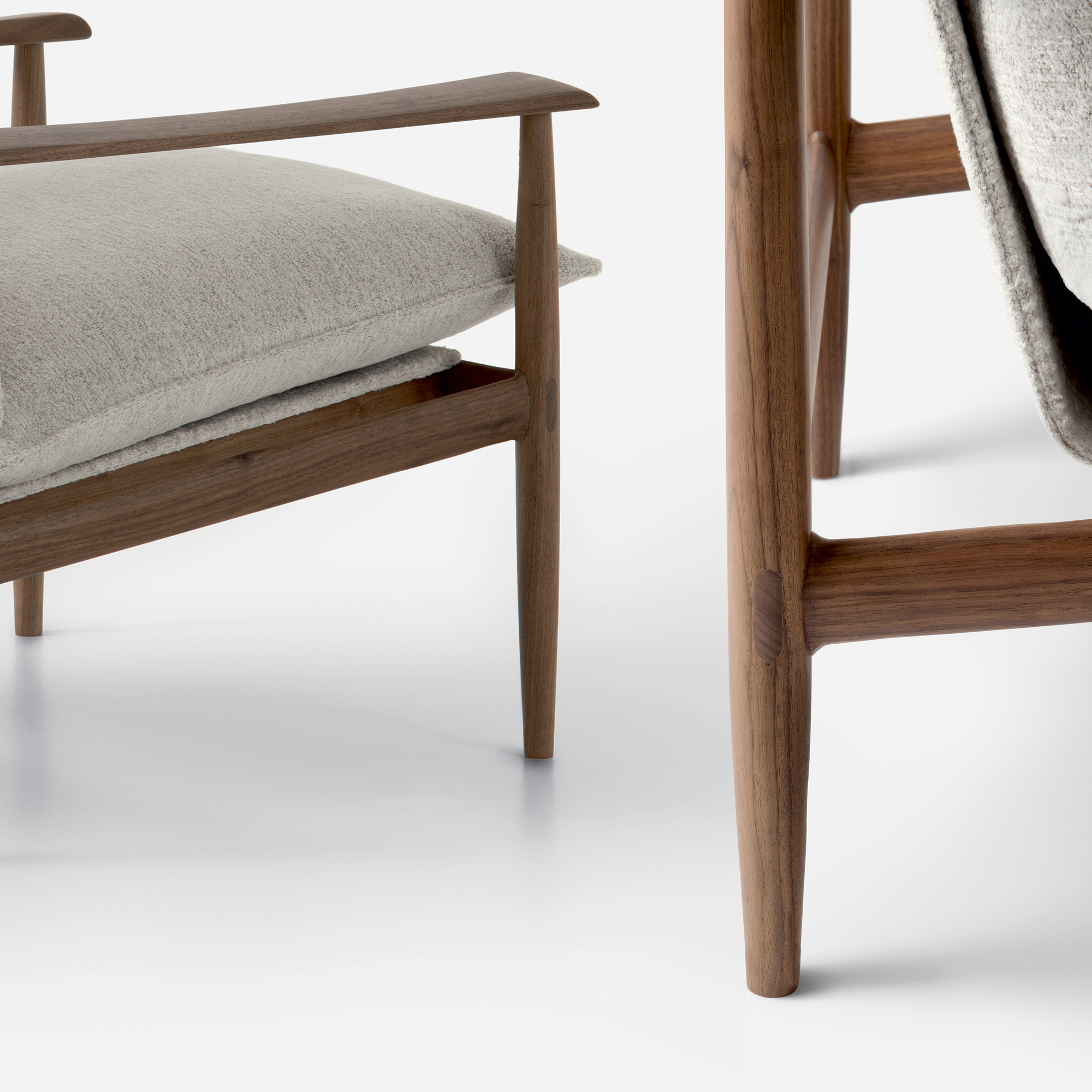 Close-up view of Giorgetti - KUMIKI's elegant wooden chair with soft, beige cushions. The design is minimalistic, highlighting the smooth wood grain and simple lines.