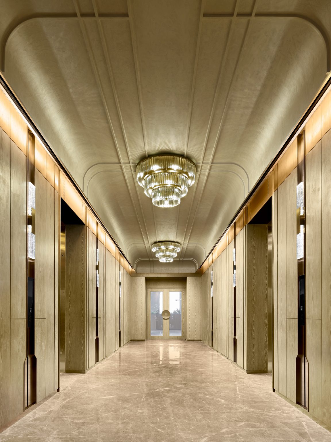 Elegant hallway with a luxurious marble floor, mirrored walls, and ornate chandeliers. The space feels grand and sophisticated, leading to a distant door.