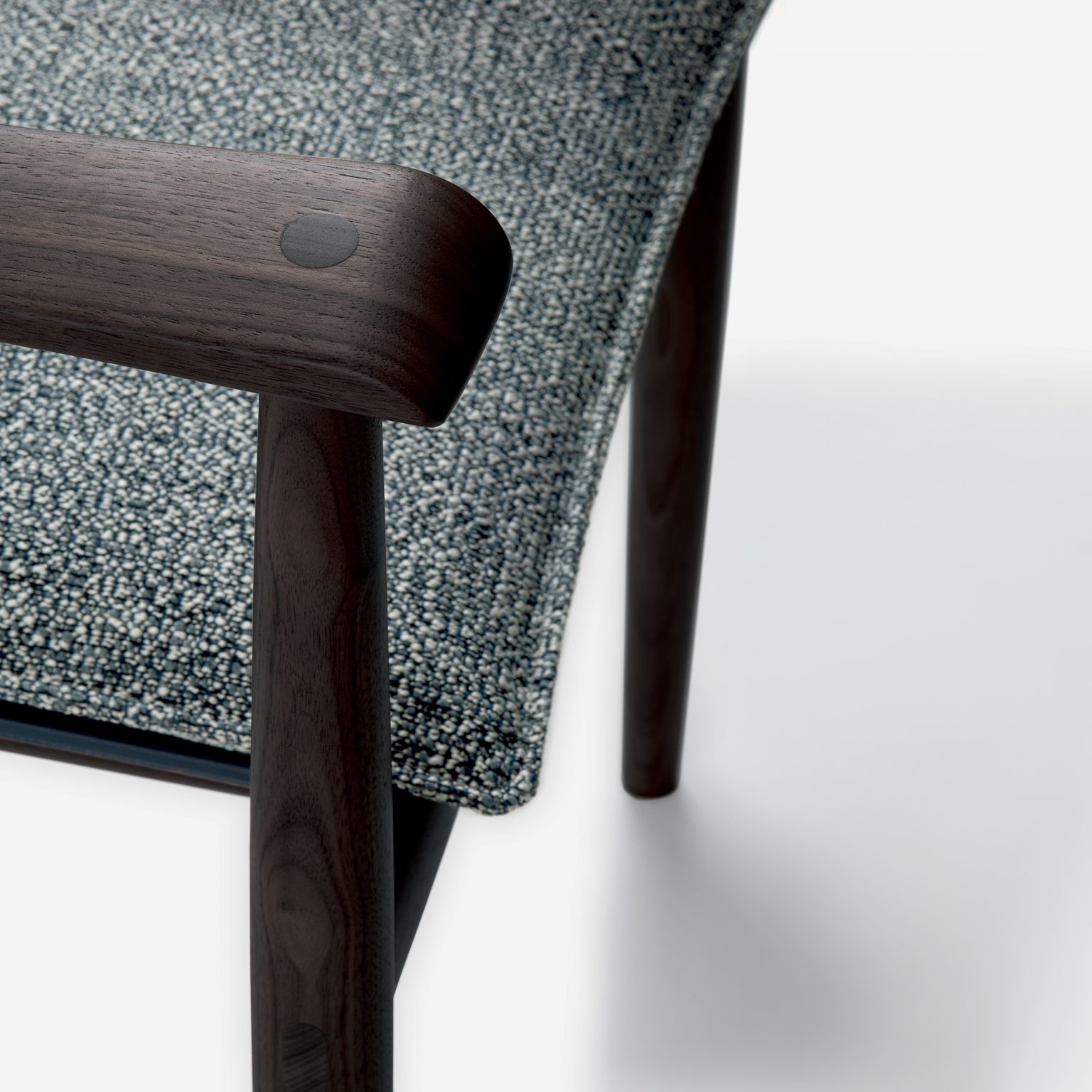 Close-up of Giorgetti - KUMIKI's chair with a textured blue-gray fabric seat and smooth, dark wood armrest. The design conveys elegance and simplicity.