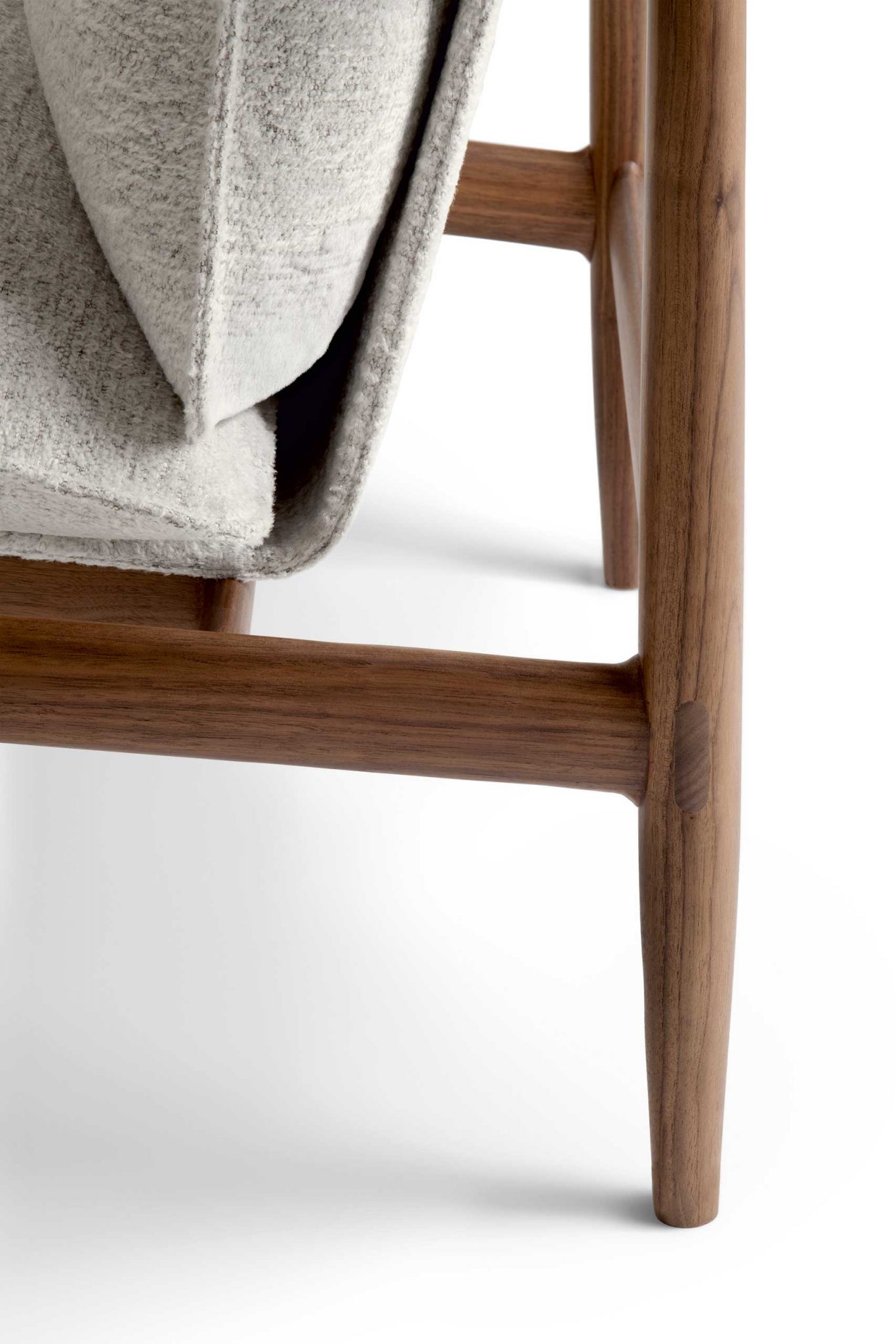 Close-up of Giorgetti Kumiki leg joint made of smooth, polished wood with a soft gray cushion. The image evokes a sense of modern elegance and minimalism.