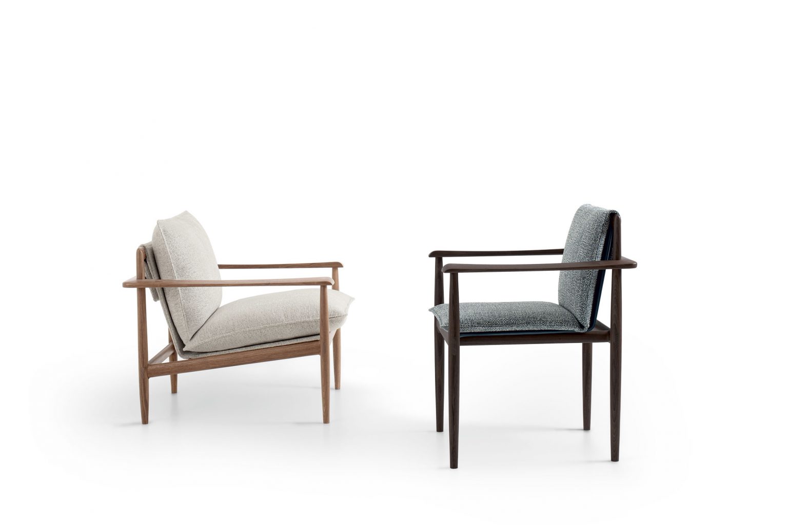 Two Giorgetti Kumiki modern armchairs on a white background; one has light beige cushions, the other dark wood with a blue back and grey cushion. Sleek and minimalist design.