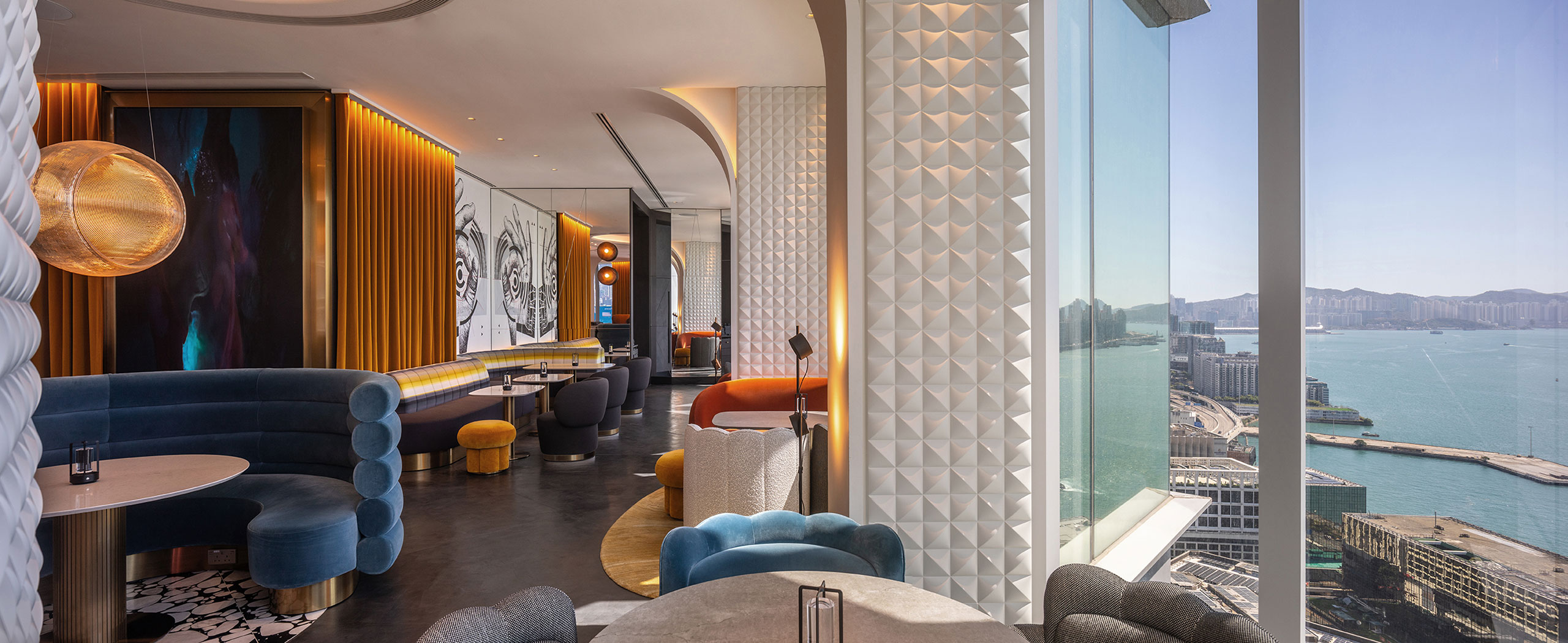 Modern lounge with vibrant colors and plush seating, featuring a panoramic view of a harbor through large windows, creating an elegant atmosphere.