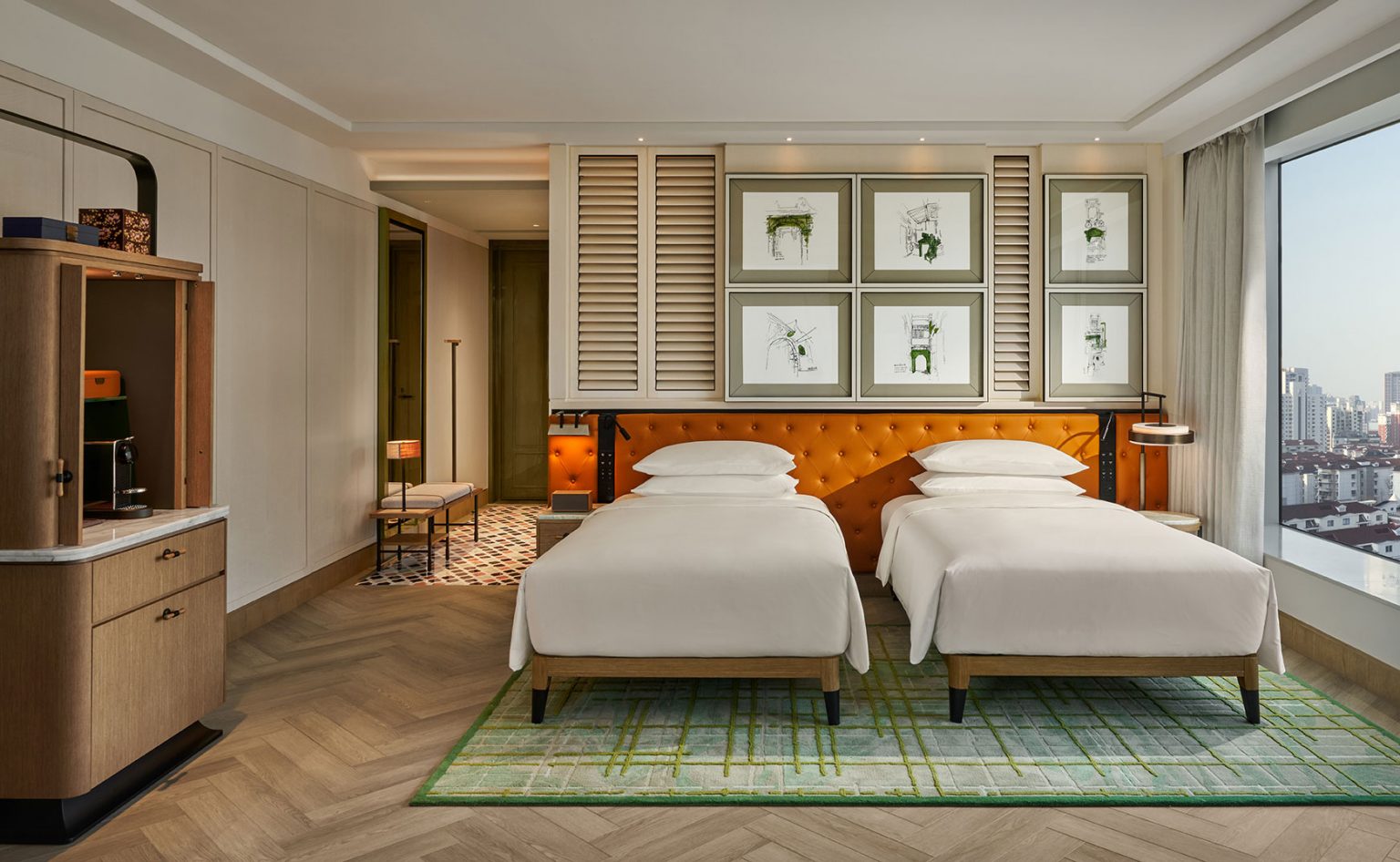 Modern hotel room with twin beds, tufted orange headboard, and framed botanical artwork. Large window reveals city skyline. Elegant and serene atmosphere.