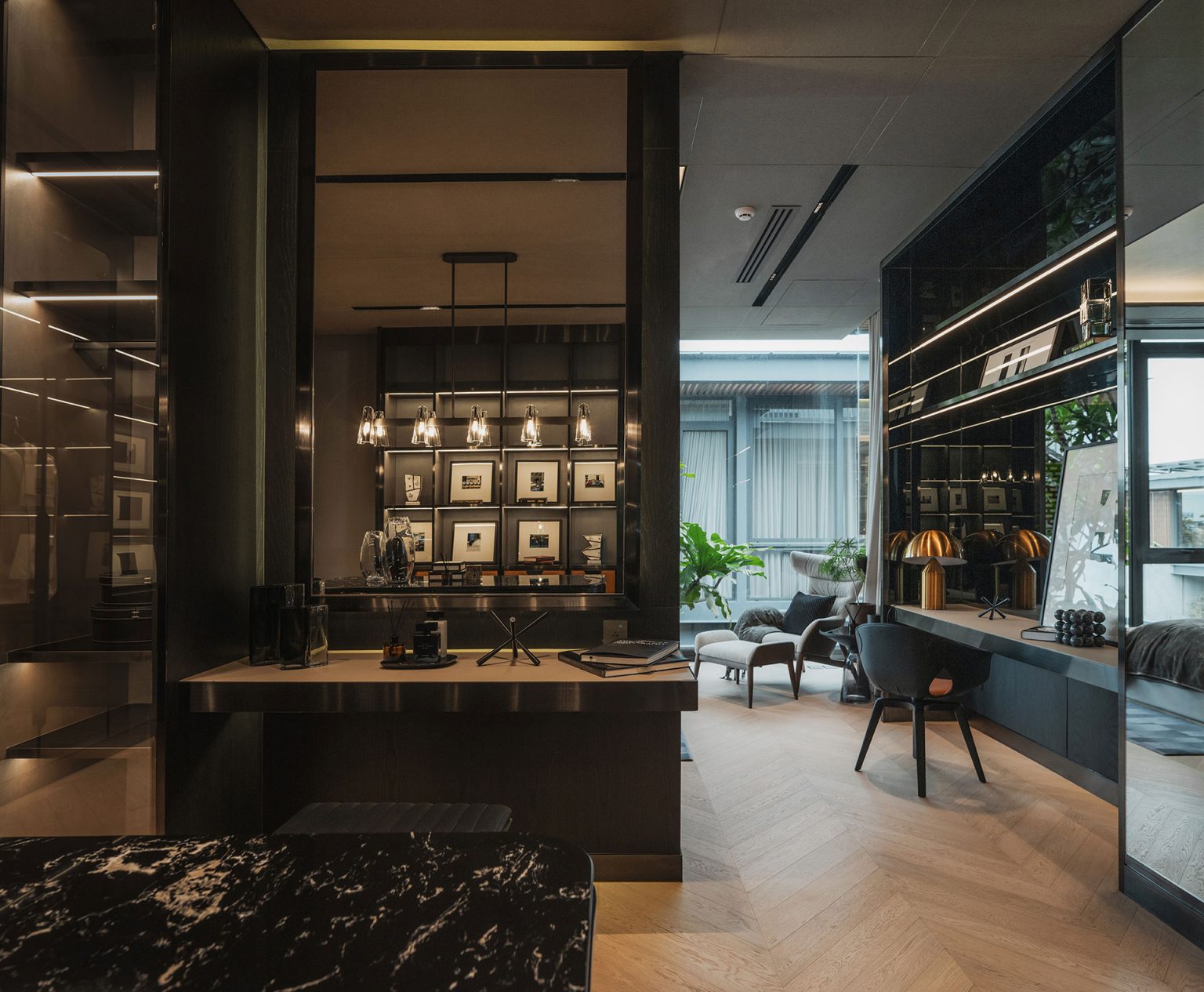 Luxurious modern office with dark wood accents, elegant shelves of framed photos, ambient pendant lighting, and a comfortable seating area.
