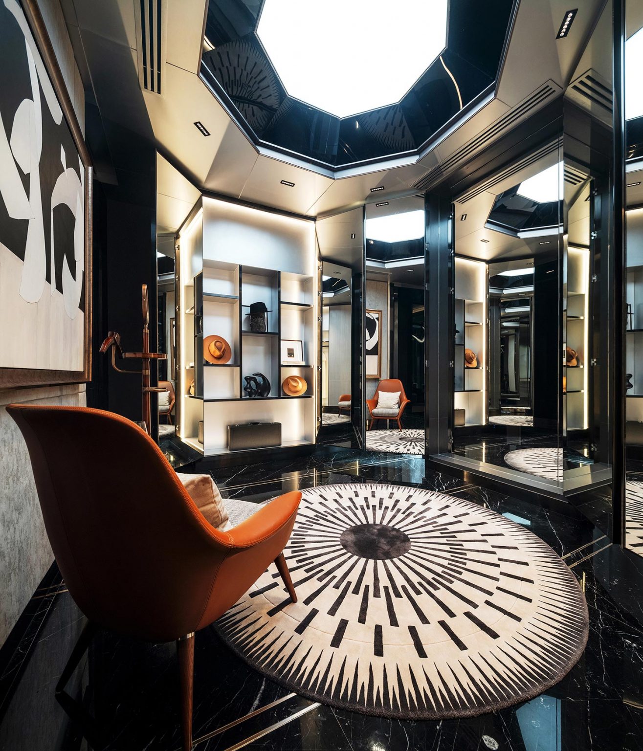 Luxurious dressing room with black marble floors, elegant orange chair, modern art, and illuminated shelves. A radial patterned rug adds sophistication.