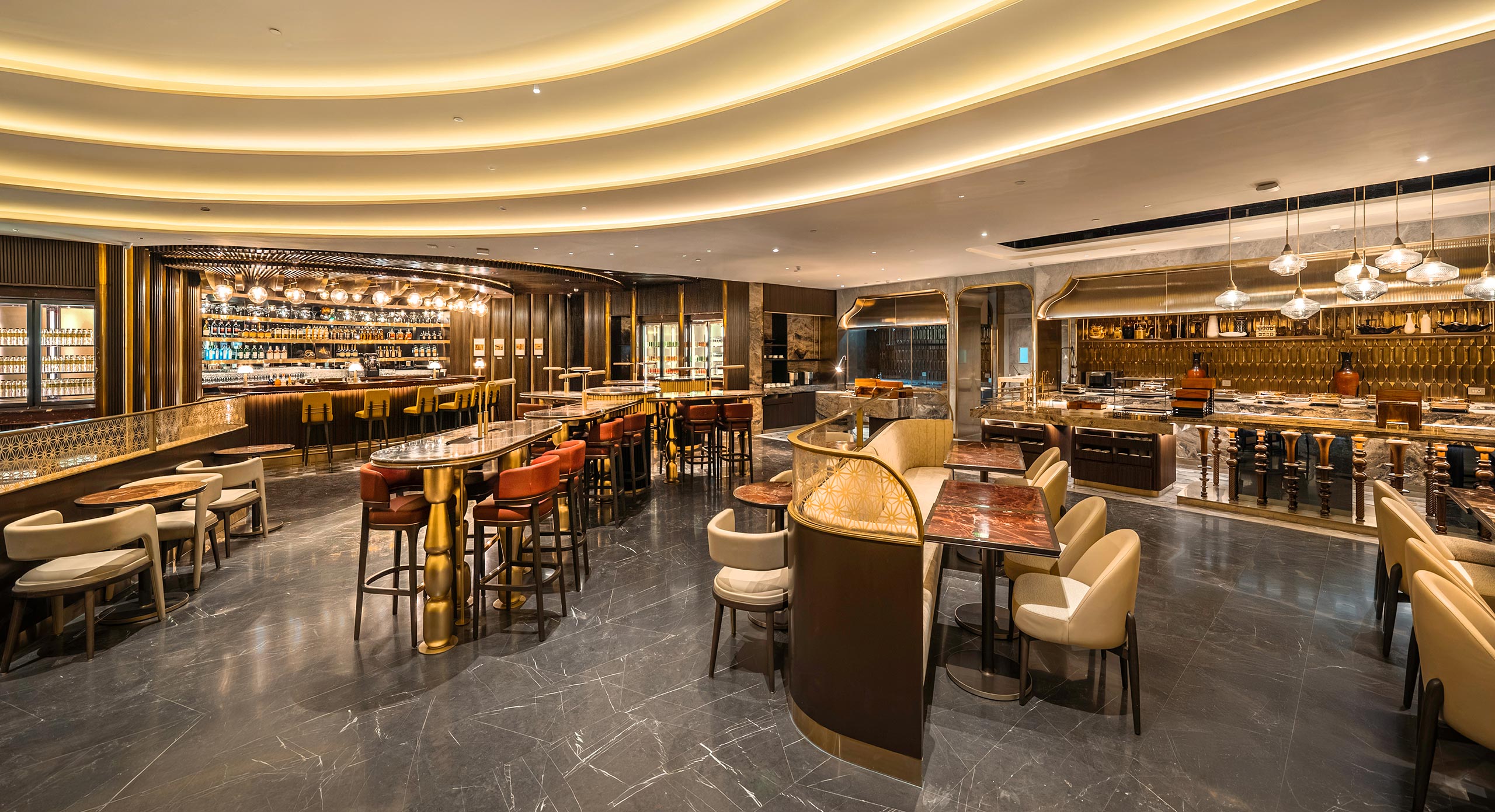 Luxurious and spacious restaurant interior with modern decor. Features include elegant lighting, a long bar, high tables with cushioned chairs, and ambient tones.