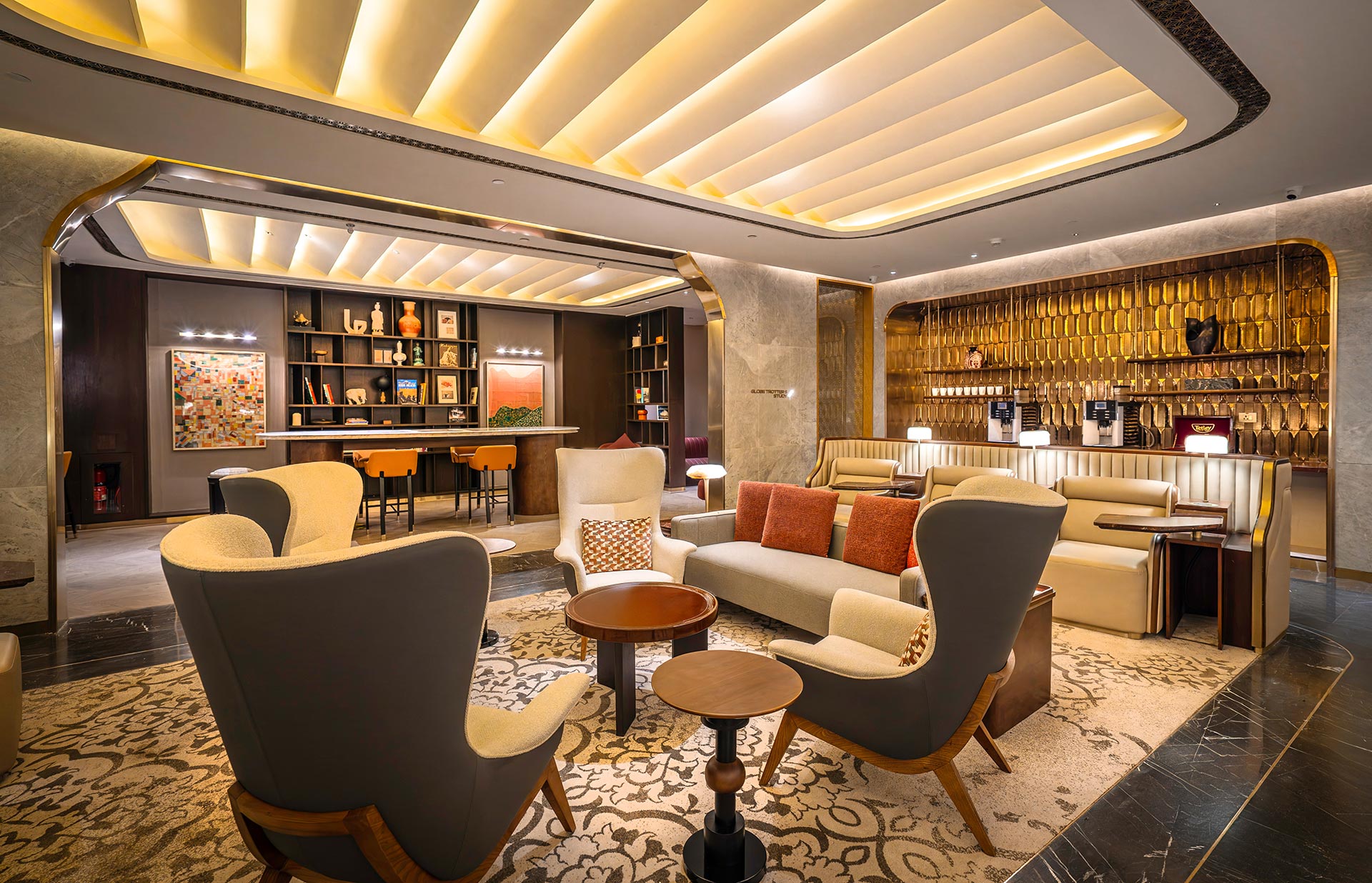 Luxurious hotel lounge with modern decor, featuring plush armchairs, a central coffee table, and a warm ambiance from soft, recessed lighting.