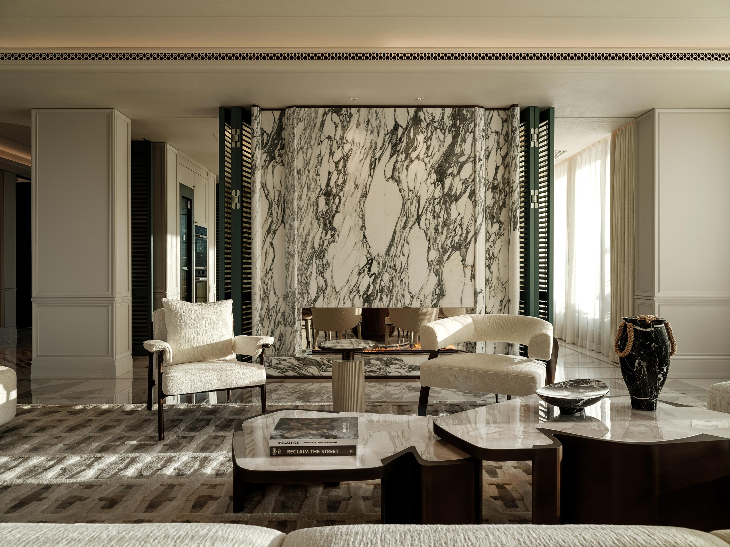 Sophisticated living room with marble wall backdrop, modern chairs, coffee table, and abstract decor. Warm natural light and elegant atmosphere.